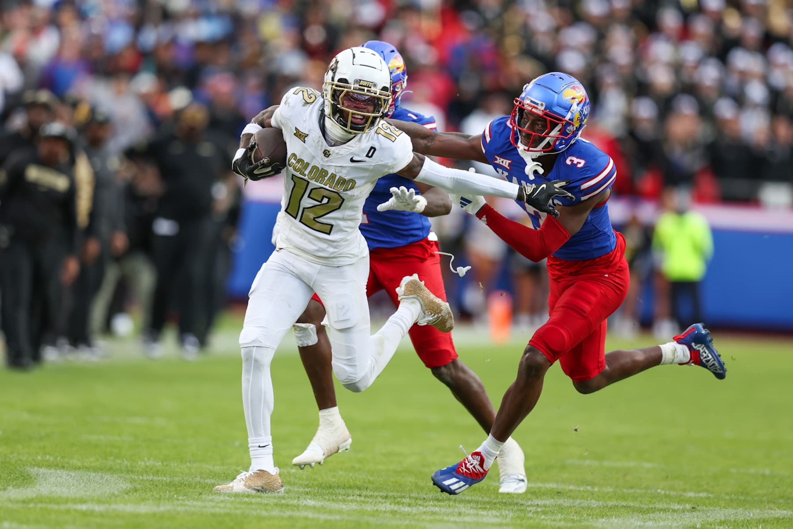 KANSAS CITY, MO - NOVEMBER 23: Colorado Buffaloes wide receiver Travis Hunter (12) tries to run away from Kansas Jayhawks defenders in the second quarter of a Big 12 game between the Colorado Buffaloes and Kansas Jayhawks on November 23, 2024 at GEHA Field at Arrowhead Stadium in Kansas City, MO. (Photo by Scott Winters/Icon Sportswire via Getty Images)