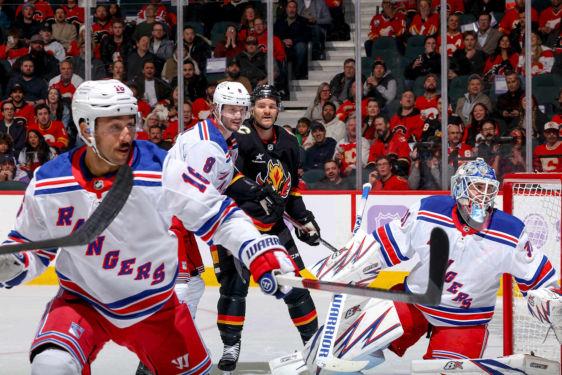 CALGARY, AB - NOVEMBER 21: Jonathan Huberdeau #10 of the Calgary Flames battles in front of the net against Jacob Trouba #8 and Igor Shesterkin #31 of the New York Rangers at Scotiabank Saddledome on November 21, 2024 in Calgary, Alberta, Canada. (Photo by Gerry Thomas/NHLI via Getty Images)