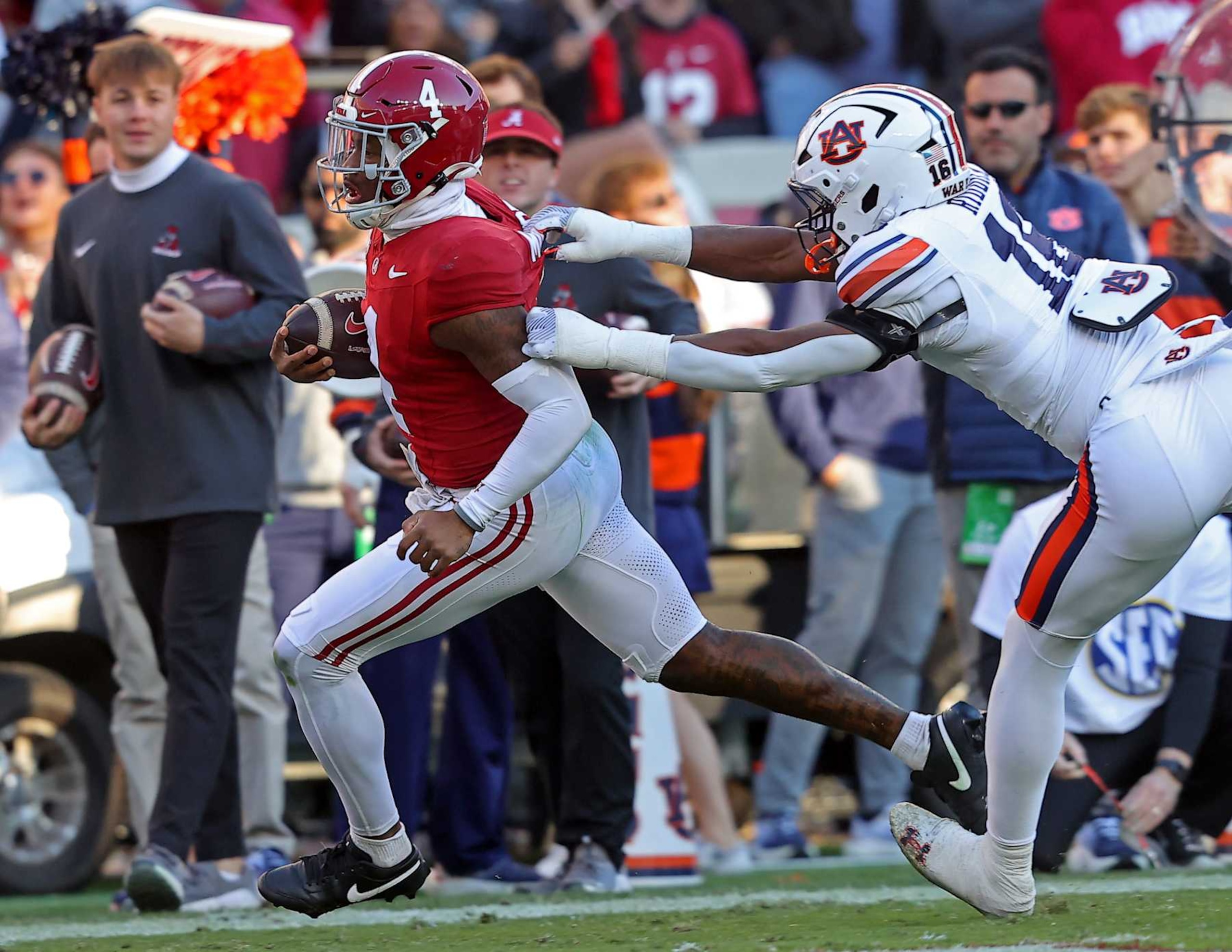 TUSCALOOSA, ALABAMA - NOVEMBER 30: Jalen Milroe #4 of the Alabama Crimson Tide breaks a tackle by Demarcus Riddick #16 of the Auburn Tigers as Milroe rushes for a touchdown during the first half at Bryant-Denny Stadium on November 30, 2024 in Tuscaloosa, Alabama. (Photo by Jason Clark/Getty Images) TUSCALOOSA, ALABAMA - NOVEMBER 30: Jalen Milroe #4 of the Alabama Crimson Tide breaks a tackle by Demarcus Riddick #16 of the Auburn Tigers as Milroe rushes for a touchdown during the first half at Bryant-Denny Stadium on November 30, 2024 in Tuscaloosa, Alabama. (Photo by Jason Clark/Getty Images)