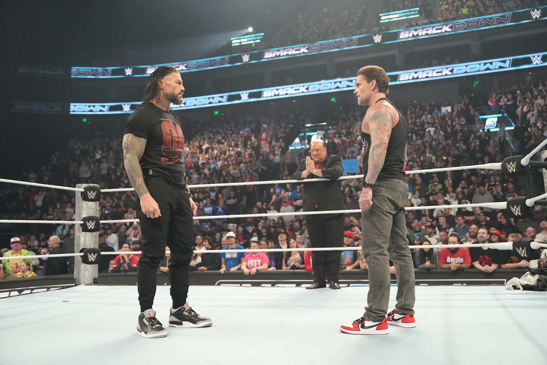 SALT LAKE CITY, UTAH - NOVEMBER 22: Roman Reigns and CM Punk in ring facing each other with Paul Herman on the ropes during WWE SmackDown at Delta Center on November 22, 2024 in Salt Lake City, Utah. (Photo by WWE/Getty Images)