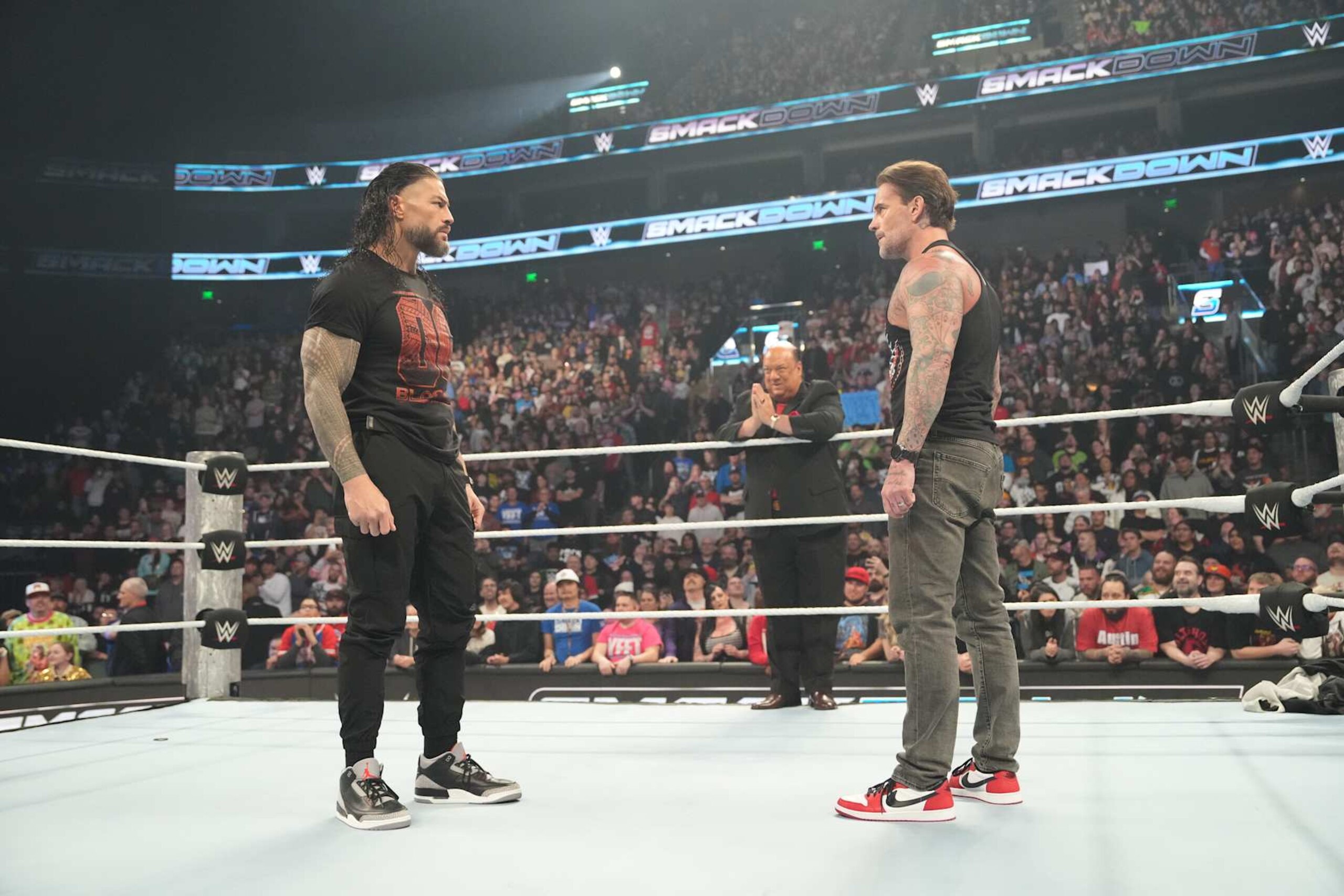 SALT LAKE CITY, UTAH - NOVEMBER 22: Roman Reigns and CM Punk in ring facing each other with Paul Herman on the ropes during WWE SmackDown at Delta Center on November 22, 2024 in Salt Lake City, Utah. (Photo by WWE/Getty Images)