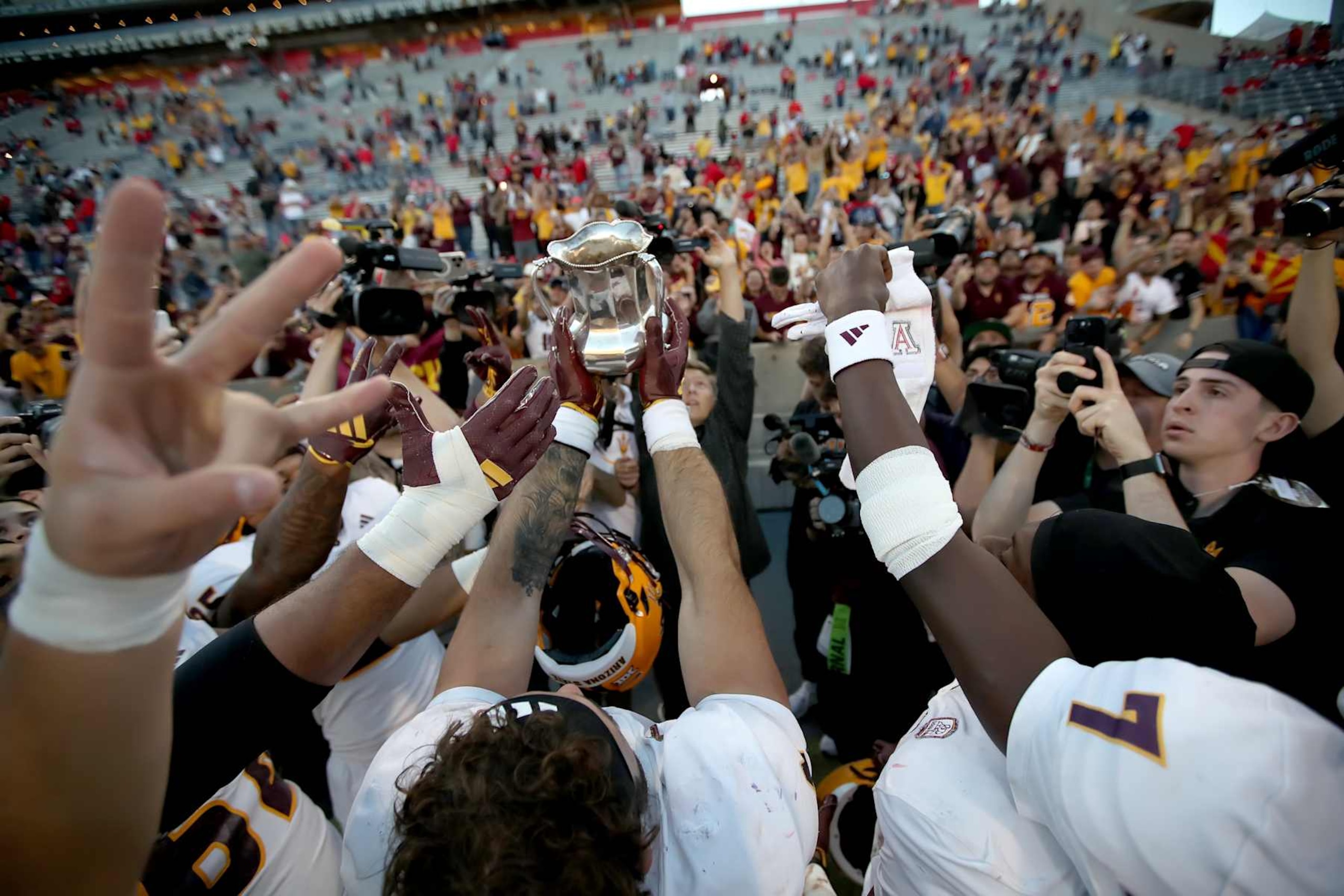 TUCSON, ARIZONA - NOVEMBER 30: Rrunningback Cam Skattebo #4 of the Arizona State Sun Devils holds up the Territorial Cup towards the Sun Devil fans after the Sun Devils defeat the Wildcats in the University of Arizona Wildcats versus the Arizona State Sun Devils football game at Arizona Stadium on November 30, 2024 in Tucson, Arizona. (Photo by Bruce Yeung/Getty Images)