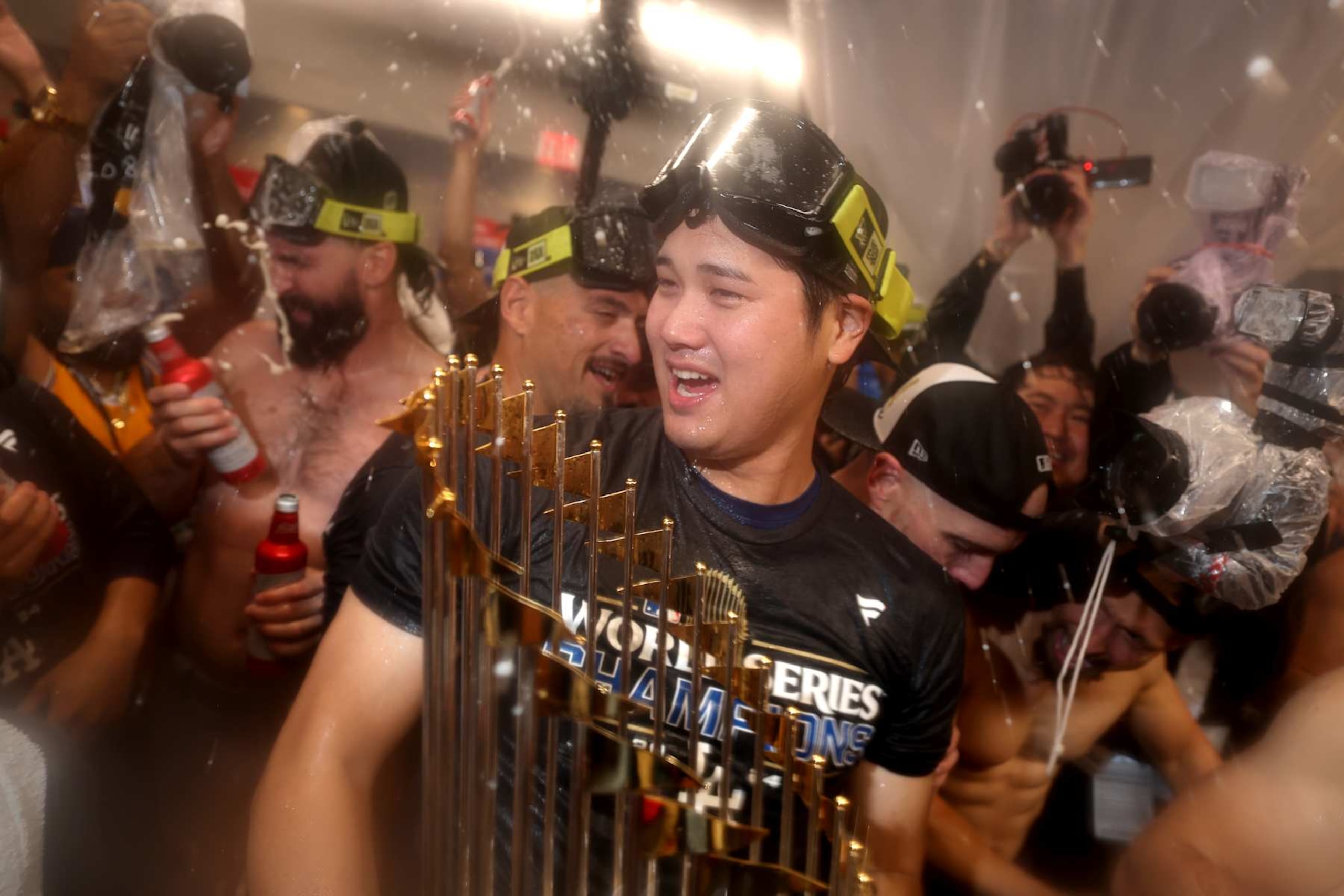 BRONX, NEW YORK - OCTOBER 30, 2024: Los Angeles Dodgers two-way player Shohei Ohtani (17) holds the World Series trophy in the locker celebration. Game 5 of the World Series against the Yankees at Yankees Stadium in New York City Wednesday, October 30 2024. (Robert Gauthier/Los Angeles Times via Getty Images)