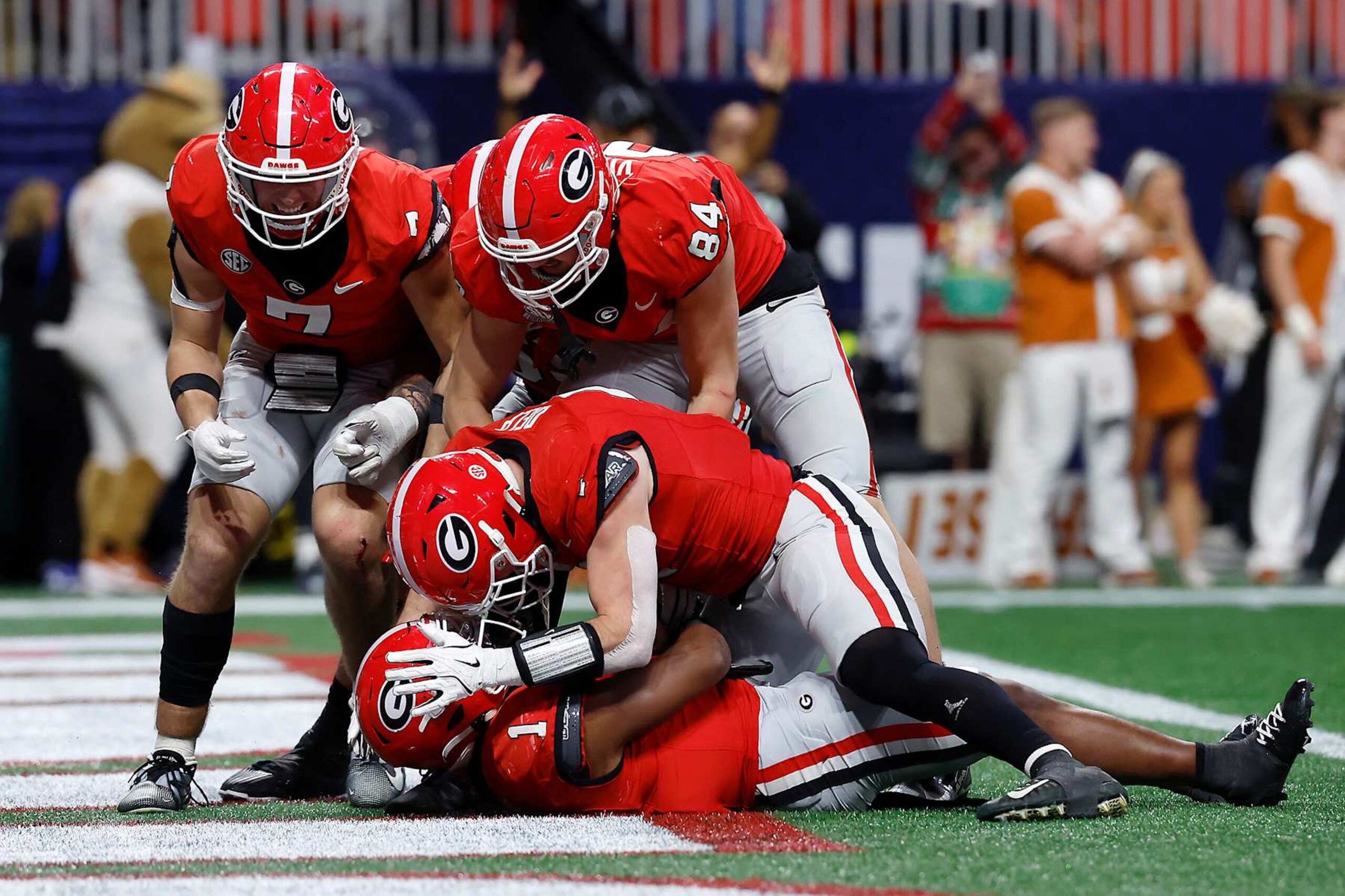 ATLANTA, GEORGIA - DECEMBER 07: Lawson Luckie #7, Ben Yurosek #84, Trevor Etienne #1 and Oscar Delp #4 of the Georgia Bulldogs celebrate a touchdown to win 22-19 against the Texas Longhorns in overtime of the 2024 SEC Championship at Mercedes-Benz Stadium on December 07, 2024 in Atlanta, Georgia. (Photo by Butch Dill/Getty Images)