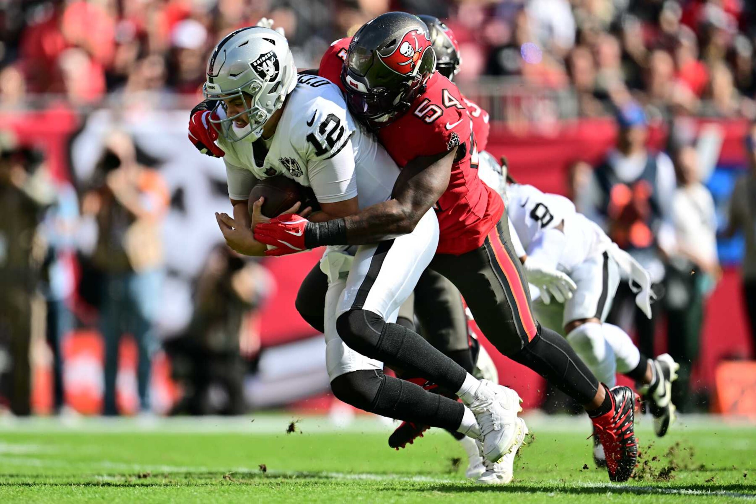 TAMPA, FLORIDA - DECEMBER 08: Aidan O'Connell #12 of the Las Vegas Raiders is sacked by Lavonte David #54 of the Tampa Bay Buccaneers during the first quarter at Raymond James Stadium on December 08, 2024 in Tampa, Florida. (Photo by Julio Aguilar/Getty Images)