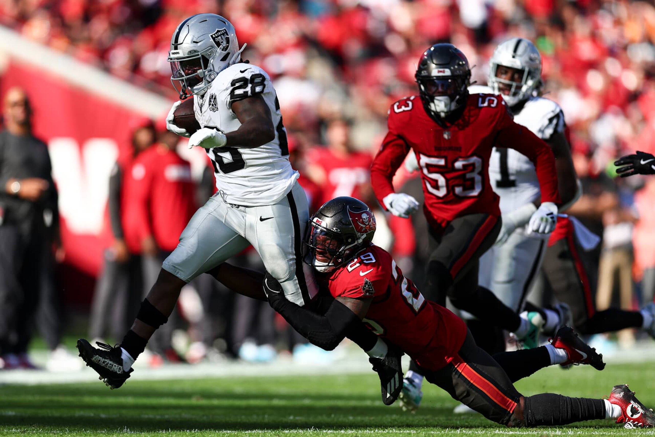 TAMPA, FLORIDA - DECEMBER 8: Christian Izien #29 of the Tampa Bay Buccaneers tackles Sincere McCormick #28 of the Las Vegas Raiders during the second half of an NFL football game at Raymond James Stadium on December 8, 2024 in Tampa, Florida. (Photo by Kevin Sabitus/Getty Images)