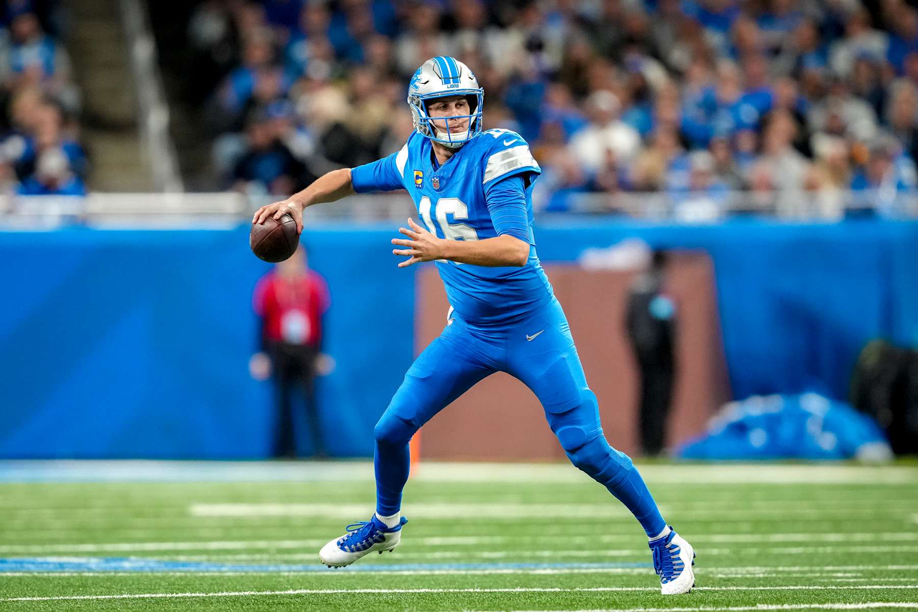 DETROIT, MICHIGAN - DECEMBER 05: Jared Goff #16 of the Detroit Lions runs and looks to throw the ball against the Green Bay Packers at Ford Field on December 05, 2024 in Detroit, Michigan. (Photo by Nic Antaya/Getty Images)