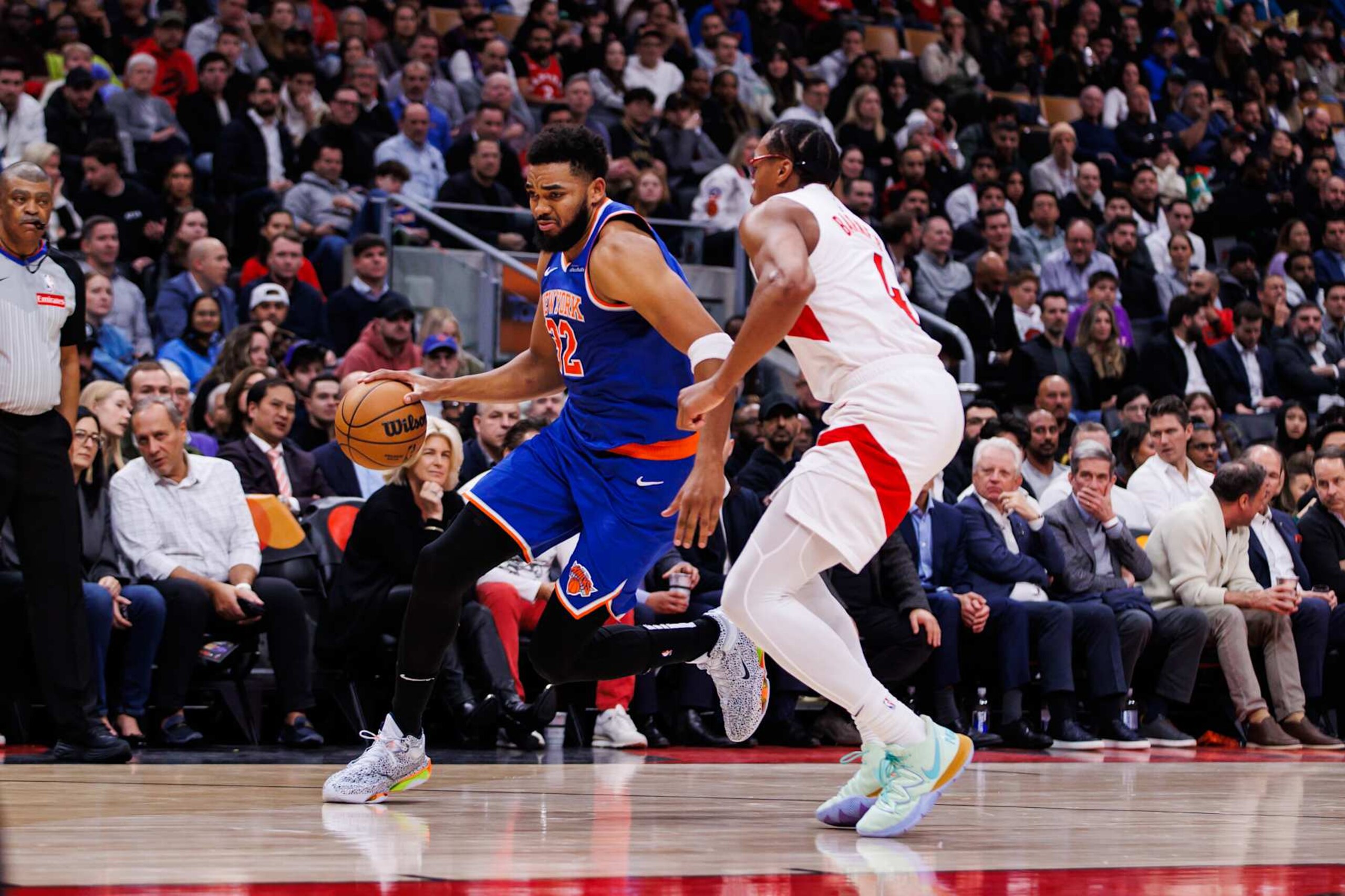 TORONTO, CANADA - DECEMBER 9: Karl-Anthony Towns #32 of the New York Knicks dribbles the ball against Scottie Barnes #4 of the Toronto Raptors during first half of their NBA game at Scotiabank Arena on December 9, 2024 in Toronto, Canada. NOTE TO USER: User expressly acknowledges and agrees that, by downloading and or using this photograph, User is consenting to the terms and conditions of the Getty Images License Agreement. (Photo by Cole Burston/Getty Images)