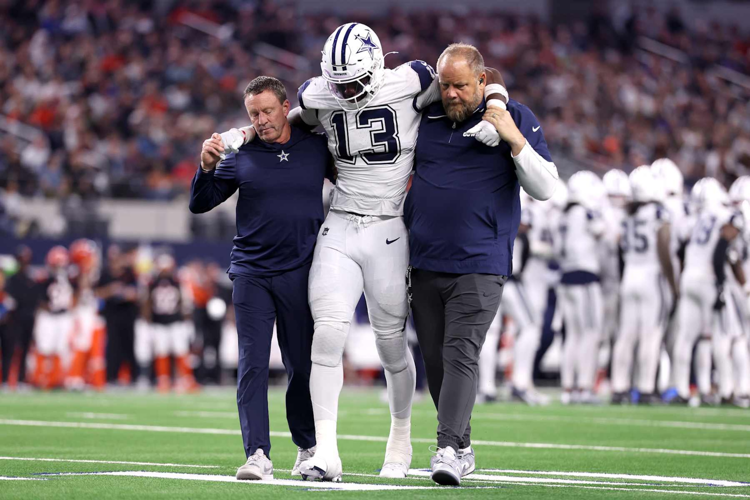 ARLINGTON, TEXAS - DECEMBER 09: DeMarvion Overshown #13 of the Dallas Cowboys is assisted off the field after a play against the Cincinnati Bengals during the fourth quarter in the game at AT&T Stadium on December 09, 2024 in Arlington, Texas. (Photo by Sam Hodde/Getty Images)