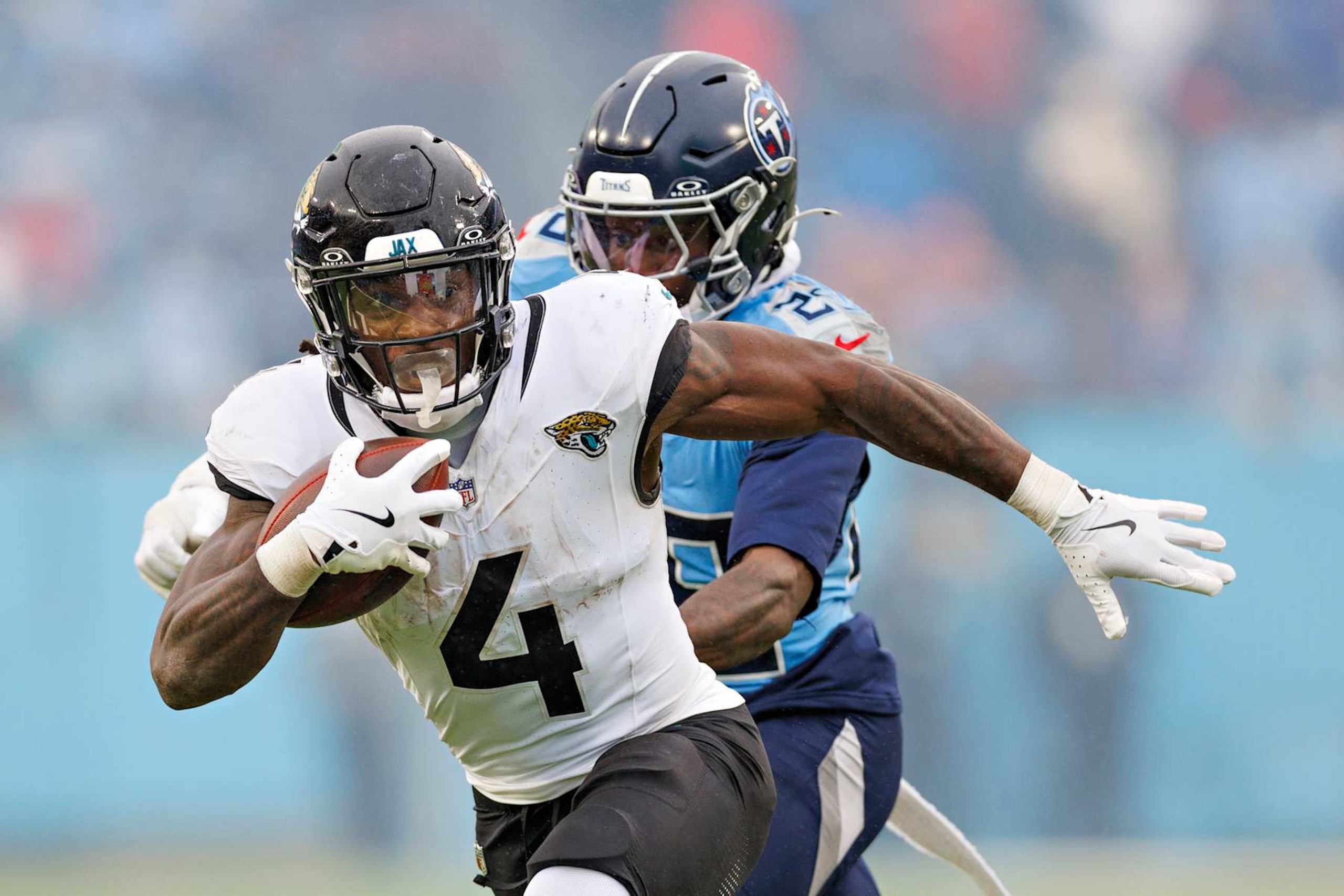 NASHVILLE, TENNESSEE - DECEMBER 8: Tank Bigsby #4 of the Jacksonville Jaguars runs the ball and is chased by Jarvis Brownlee Jr. #29 of the Tennessee Titans at Nissan Stadium on December 8, 2024 in Nashville, Tennessee. The Jaguars defeated the Titans 10-6.  (Photo by Wesley Hitt/Getty Images)
