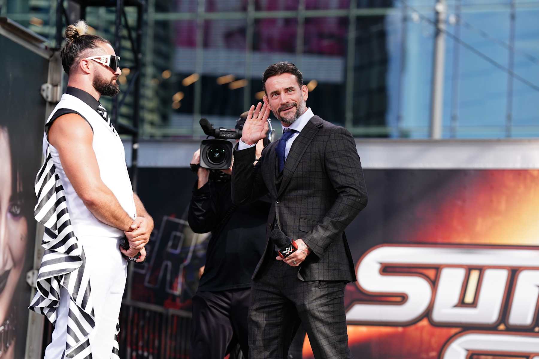 CLEVELAND, OHIO - AUGUST 2: Seth Rollins and CM Punk listen to the crowd during the WWE SummerSlam Kickoff at Rocket Mortgage FieldHouse on August 2, 2024 in Cleveland, Ohio. (Photo by WWE/Getty Images)