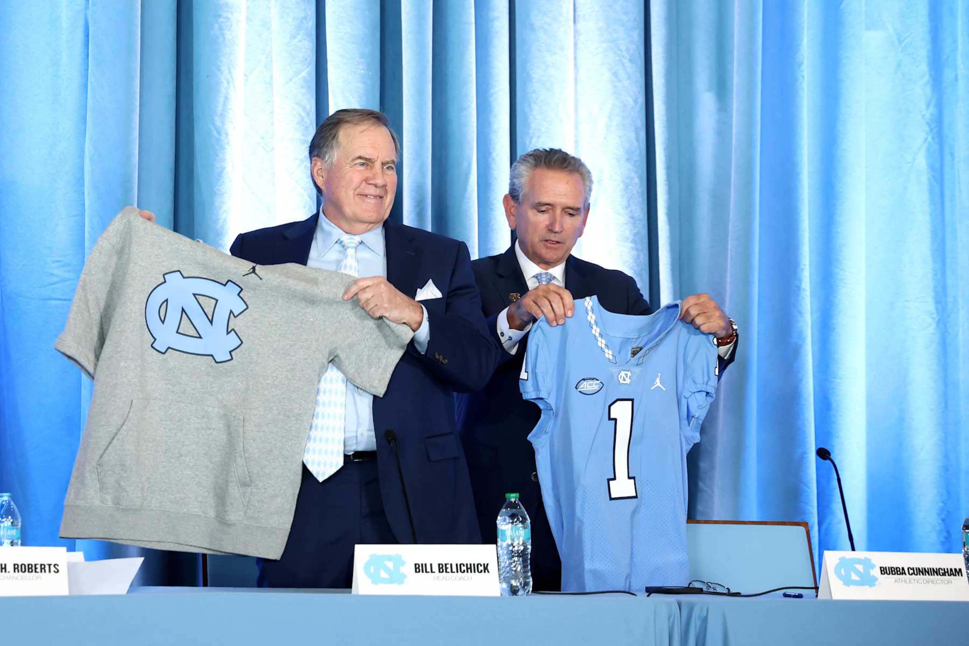 CHAPEL HILL, NORTH CAROLINA - DECEMBER 12: Head Coach Bill Belichick of the North Carolina Tar Heels poses with Athletic director Bubba Cunningham during a press conference on December 12, 2024 in Chapel Hill, North Carolina. (Photo by Jared C. Tilton/Getty Images) CHAPEL HILL, NORTH CAROLINA - DECEMBER 12: Head Coach Bill Belichick of the North Carolina Tar Heels poses with Athletic director Bubba Cunningham during a press conference on December 12, 2024 in Chapel Hill, North Carolina. (Photo by Jared C. Tilton/Getty Images)