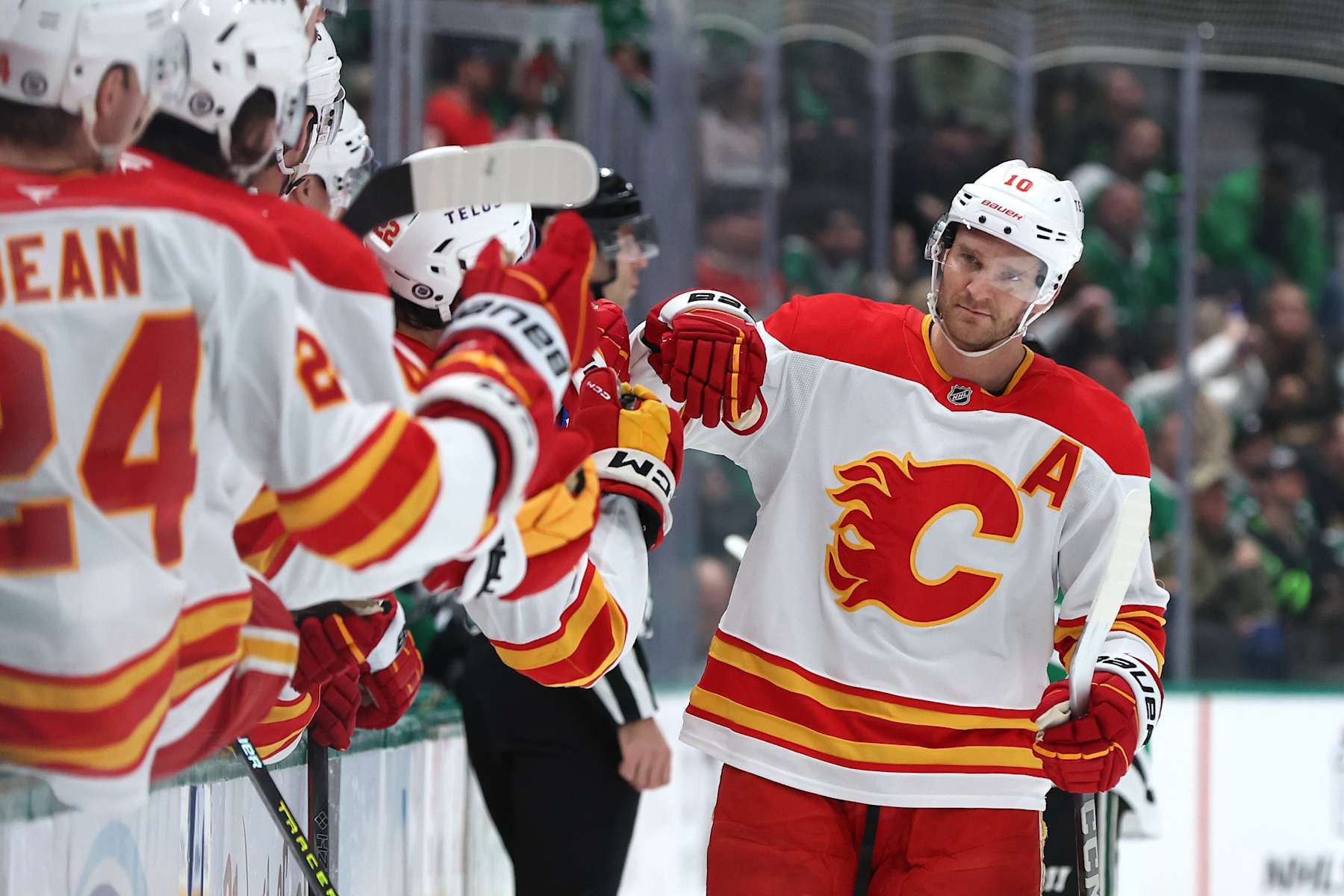DALLAS, TEXAS - DECEMBER 08: Jonathan Huberdeau #10 of the Calgary Flames is congratulated by his bench after scoring a goal during the first period against the Dallas Stars at American Airlines Center on December 08, 2024 in Dallas, Texas. (Photo by Sam Hodde/Getty Images)