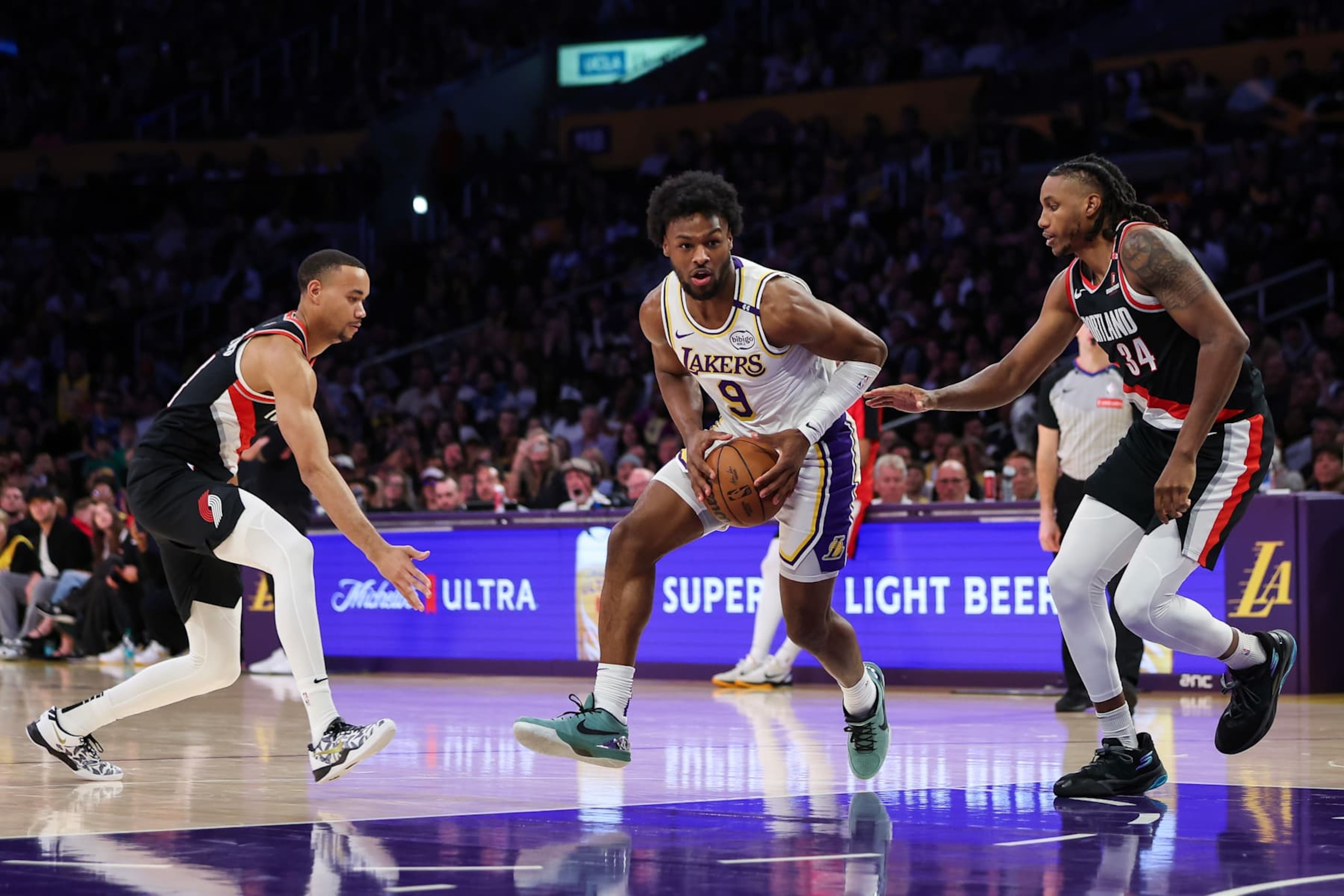 LOS ANGELES, CALIFORNIA - DECEMBER 08: Bronny James #9 of the Los Angeles Lakers drives with the ball between Jabari Walker #34 and Bryce McGowens #11 of the Portland Trail Blazers in the second half at Crypto.com Arena on December 08, 2024 in Los Angeles, California. NOTE TO USER: User expressly acknowledges and agrees that, by downloading and or using this Photograph, user is consenting to the terms and conditions of the Getty Images License Agreement. (Photo by Meg Oliphant/Getty Images)
