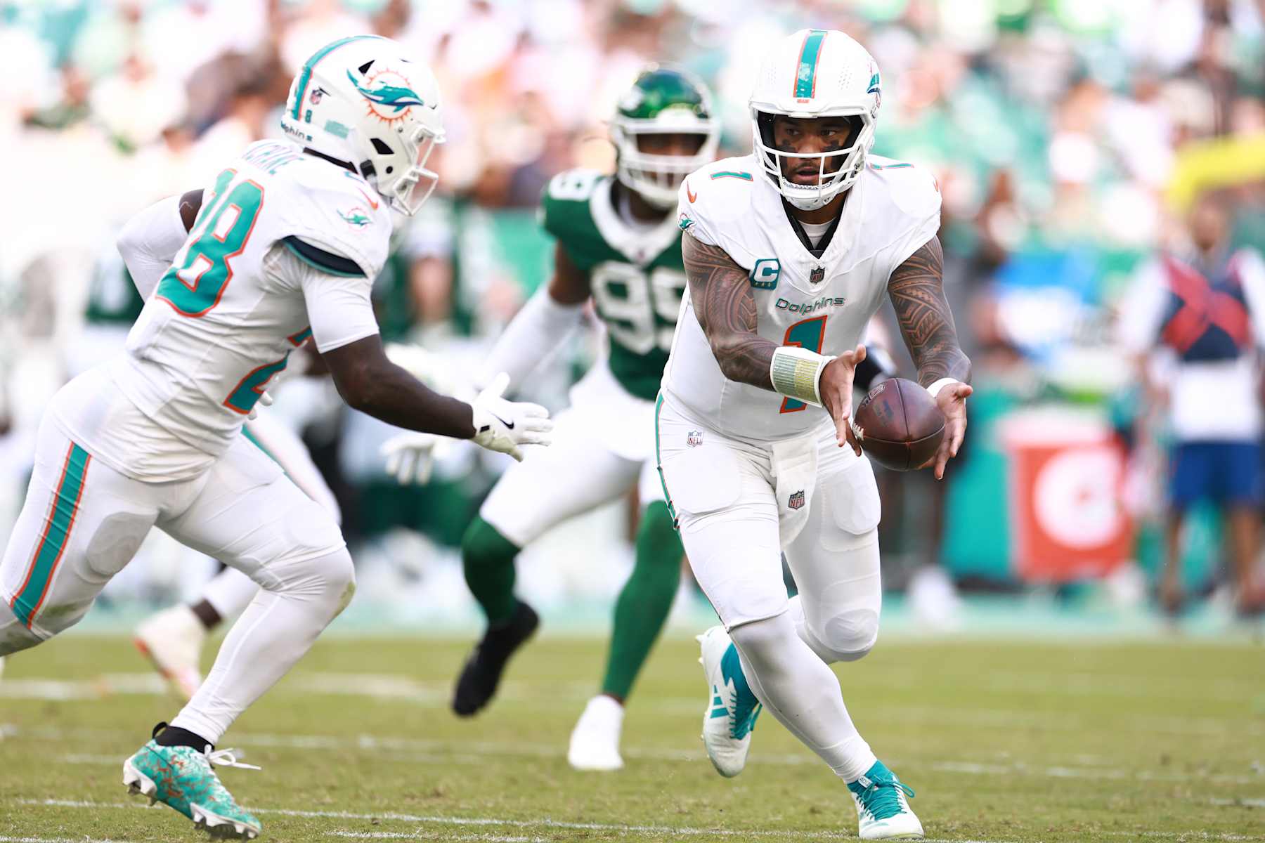 MIAMI GARDENS, FLORIDA - DECEMBER 08: Tua Tagovailoa #1 of the Miami Dolphins pitches the ball to De'Von Achane #28 in the third quarter of a game against the New York Jets at Hard Rock Stadium on December 08, 2024 in Miami Gardens, Florida. (Photo by Carmen Mandato/Getty Images)