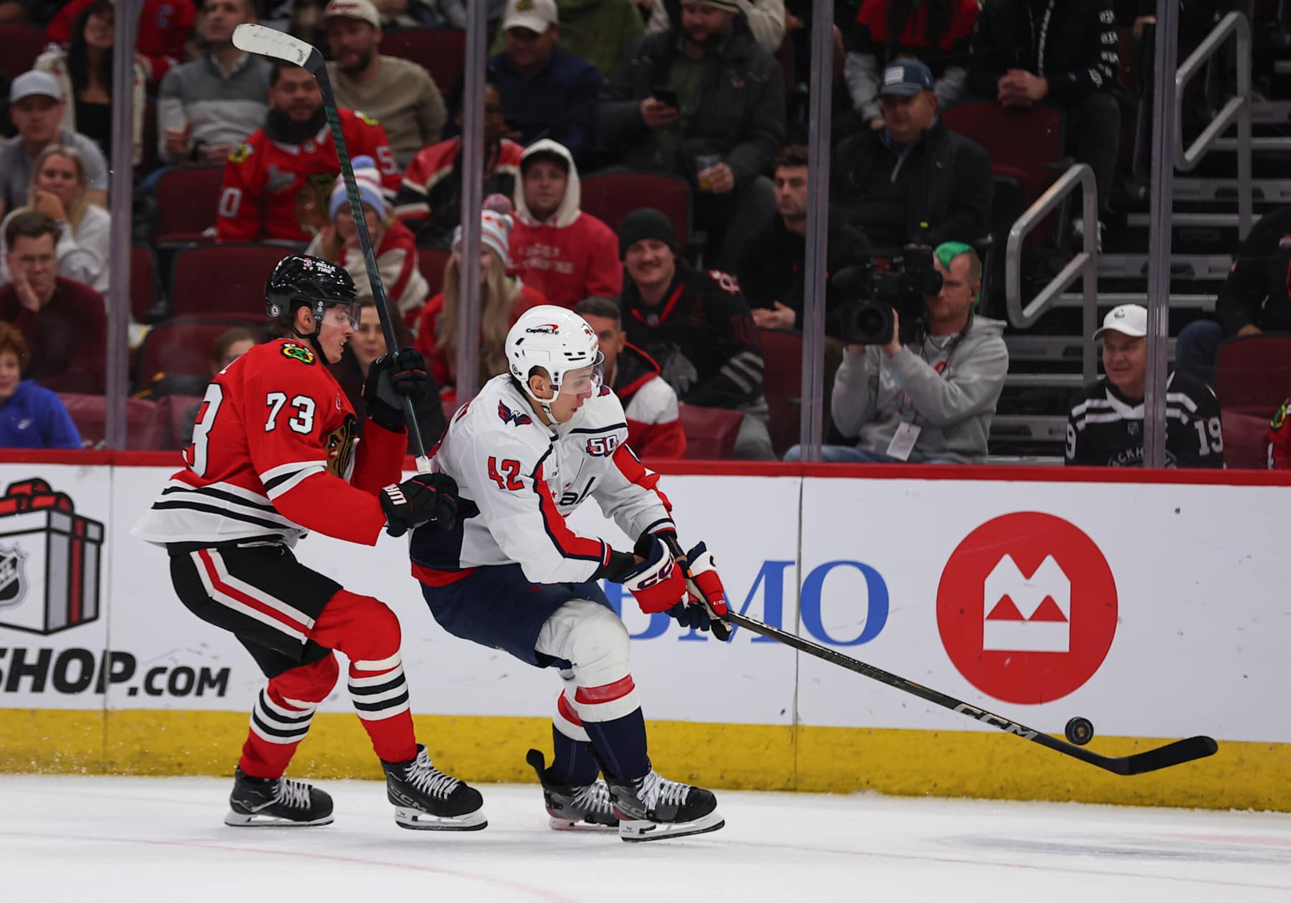 CHICAGO, IL - DECEMBER 17: Martin Fehervary #42 of the Washington Capitals controls the puck against  Lukas Reichel #73 of the Chicago Blackhawks during the third period on December 17, 2024 at the United Center in Chicago, Illinois. (Photo by Melissa Tamez/Icon Sportswire via Getty Images)