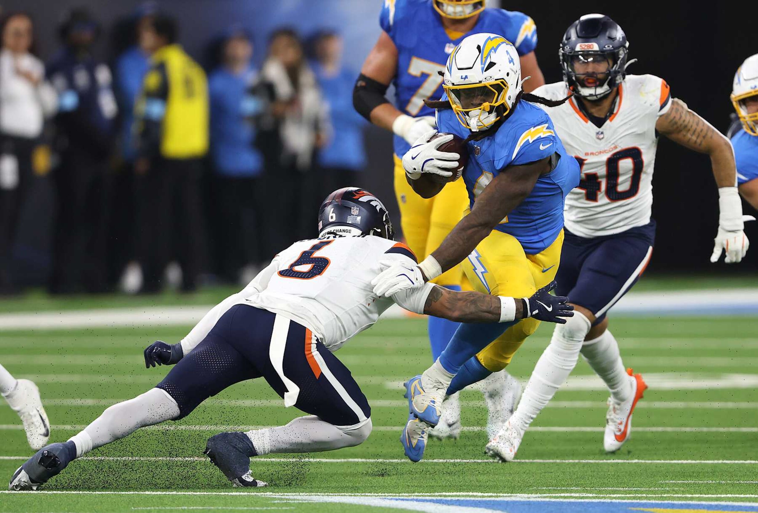 INGLEWOOD, CALIFORNIA - DECEMBER 19: Gus Edwards #4 of the Los Angeles Chargers runs the ball against P.J. Locke #6 of the Denver Broncos during the fourth quarter in the game at SoFi Stadium on December 19, 2024 in Inglewood, California. (Photo by Sean M. Haffey/Getty Images)