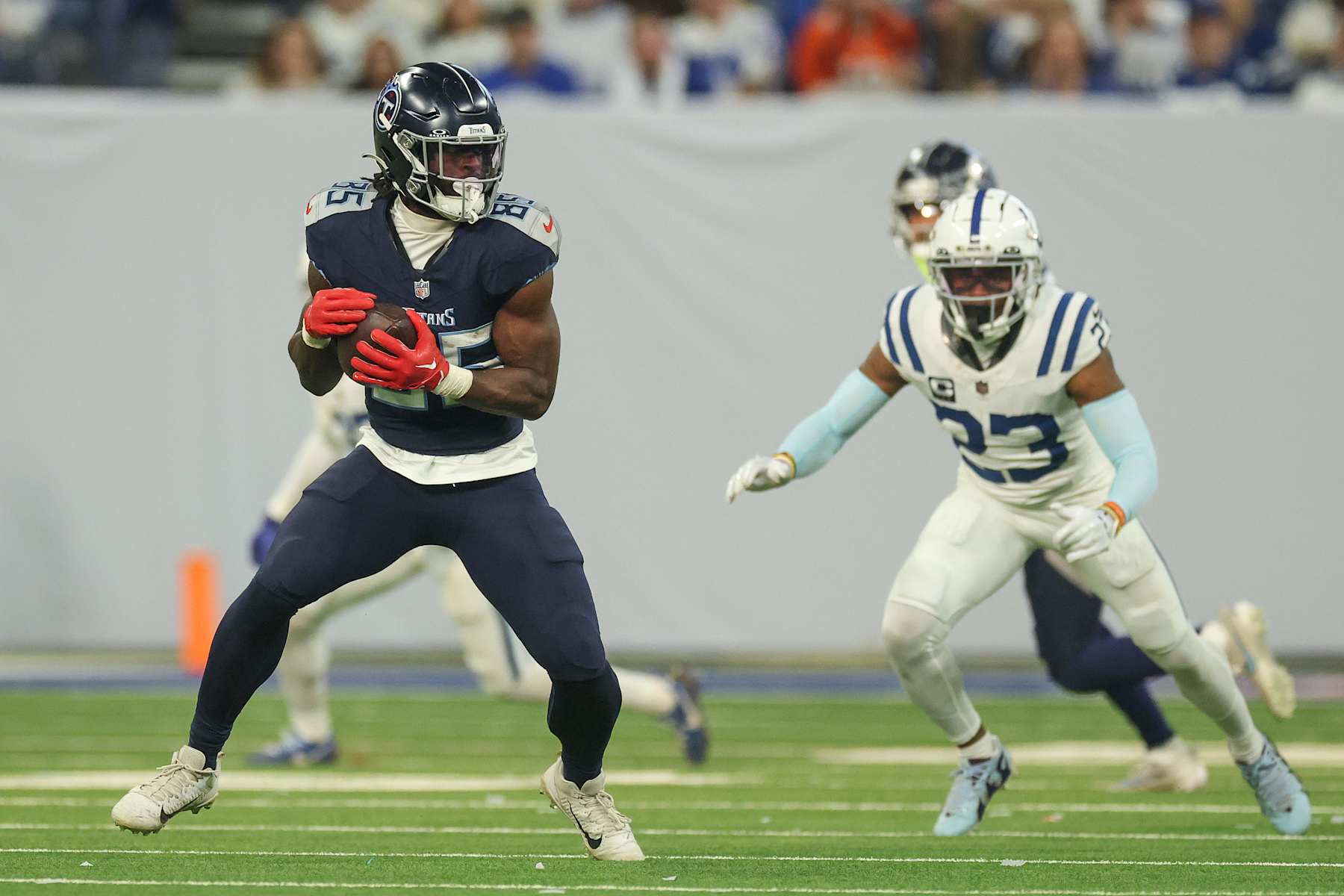 INDIANAPOLIS, INDIANA - DECEMBER 22: Chig Okonkwo #85 of the Tennessee Titans runs with the ball against Kenny Moore II #23 of the Indianapolis Colts during the second half at Lucas Oil Stadium on December 22, 2024 in Indianapolis, Indiana. (Photo by Andy Lyons/Getty Images)