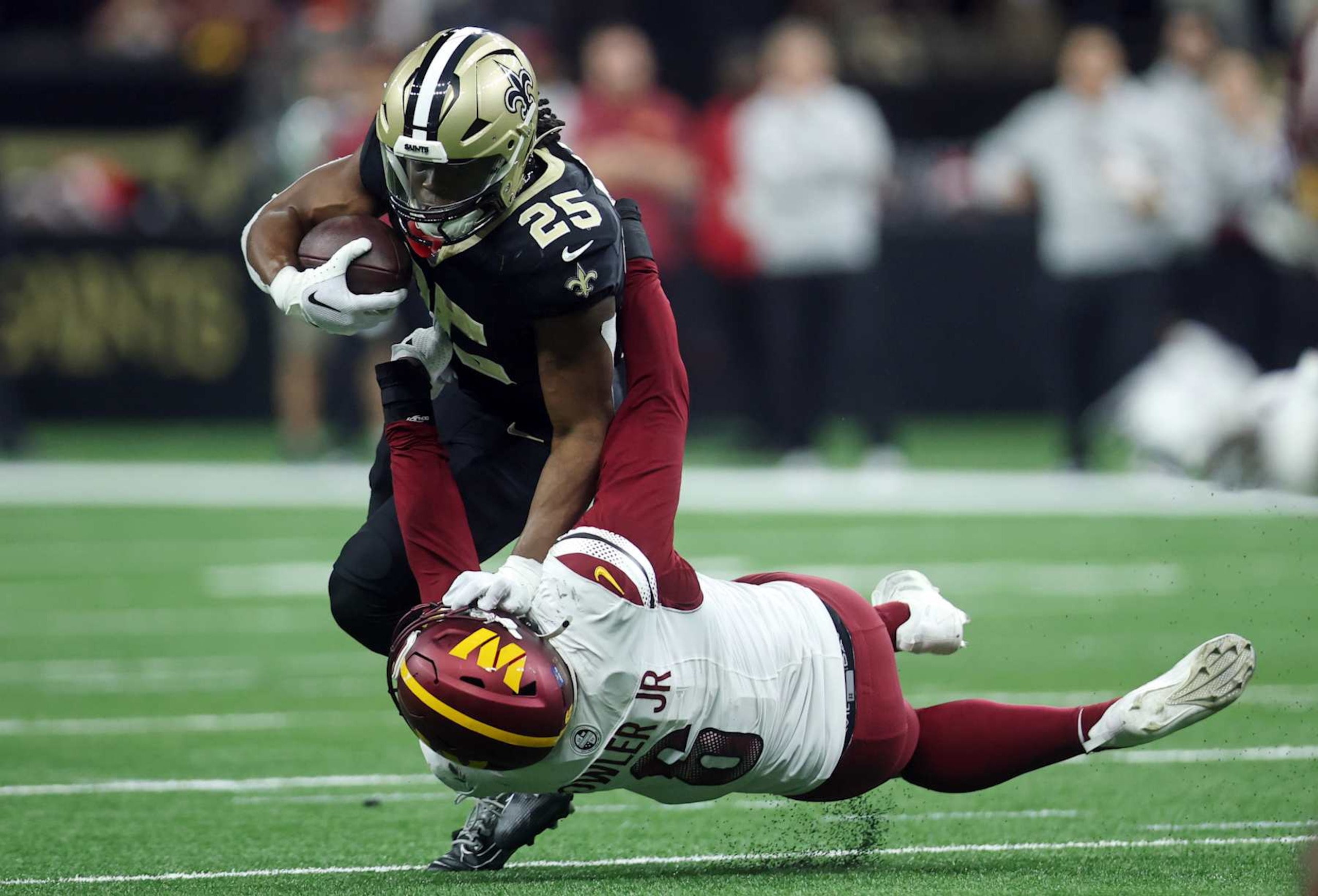 NEW ORLEANS, LOUISIANA - DECEMBER 15: Kendre Miller #25 of the New Orleans Saints is tackled by Dante Fowler Jr. #6 of the Washington Commanders during the second half at Caesars Superdome on December 15, 2024 in New Orleans, Louisiana. (Photo by Chris Graythen/Getty Images)