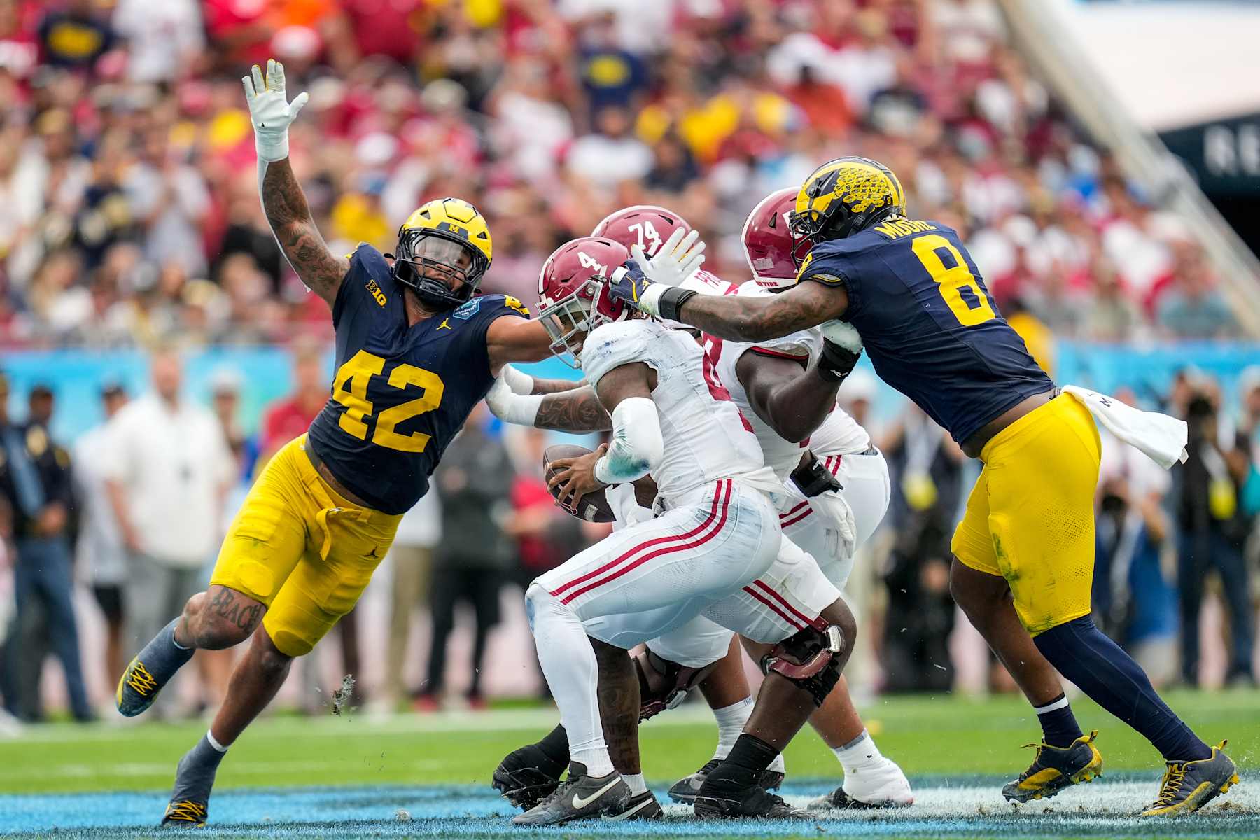TAMPA, FL - DECEMBER 31: Michigan Wolverines defensive end TJ Guy (42) and Michigan Wolverines defensive end Derrick Moore (8) heavily pursues Alabama Crimson Tide quarterback Jalen Milroe (4) during the ReliaQuest Bowl between the Alabama Crimson Tide and the Michigan Wolverines, December 31, 2024 at Raymond James Stadium in Tampa, Florida. (Photo by Ricky Bowden/Icon Sportswire via Getty Images)