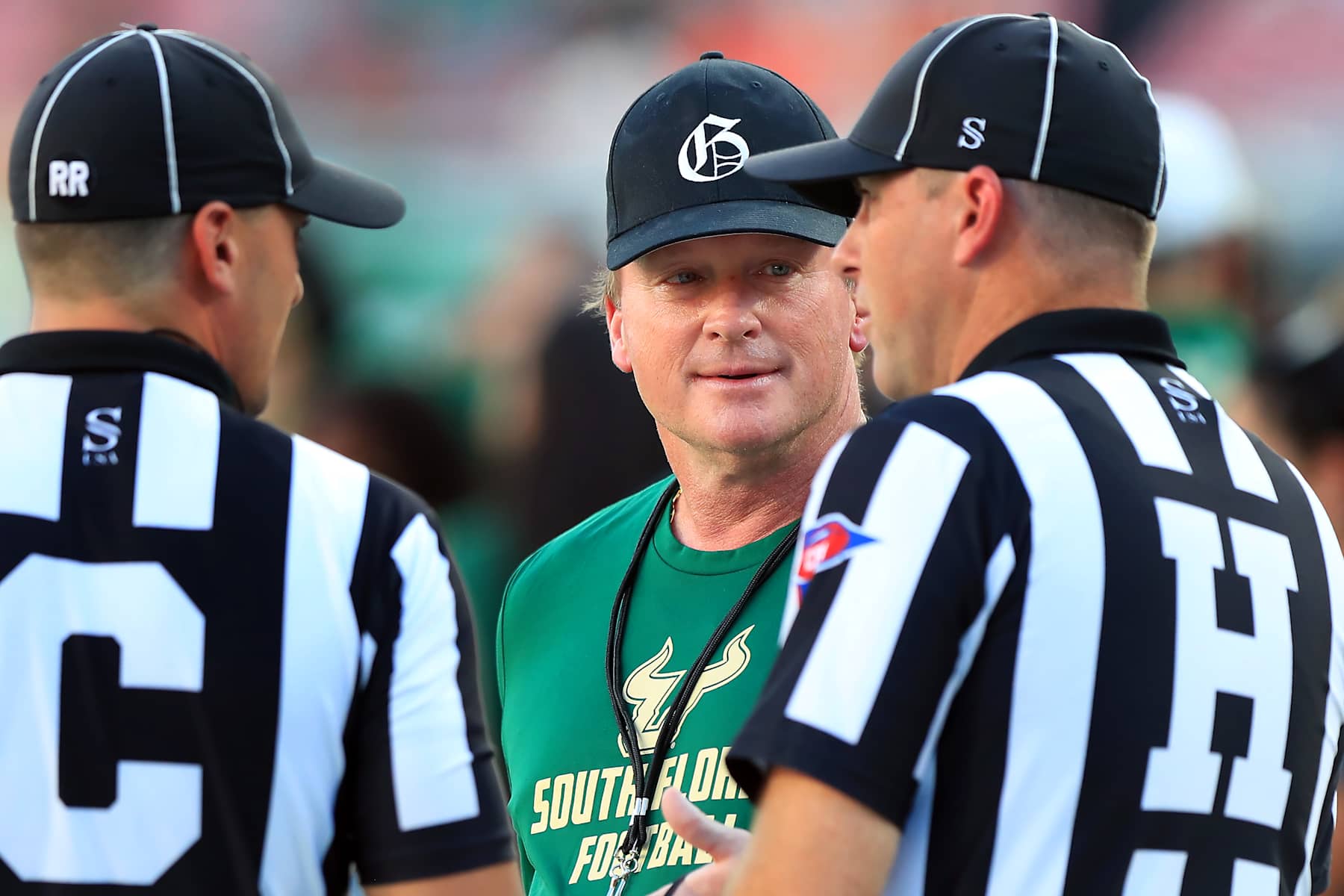 TAMPA, FL - SEPTEMBER 21: Former Tampa Bay Buccaneers Head Coach Jon Gruden talks with two game officials before the College Football game between the Miami Hurricanes and the South Florida Bulls on September 21, 2024 at Raymond James Stadium in Tampa, FL. (Photo by Cliff Welch/Icon Sportswire via Getty Images)