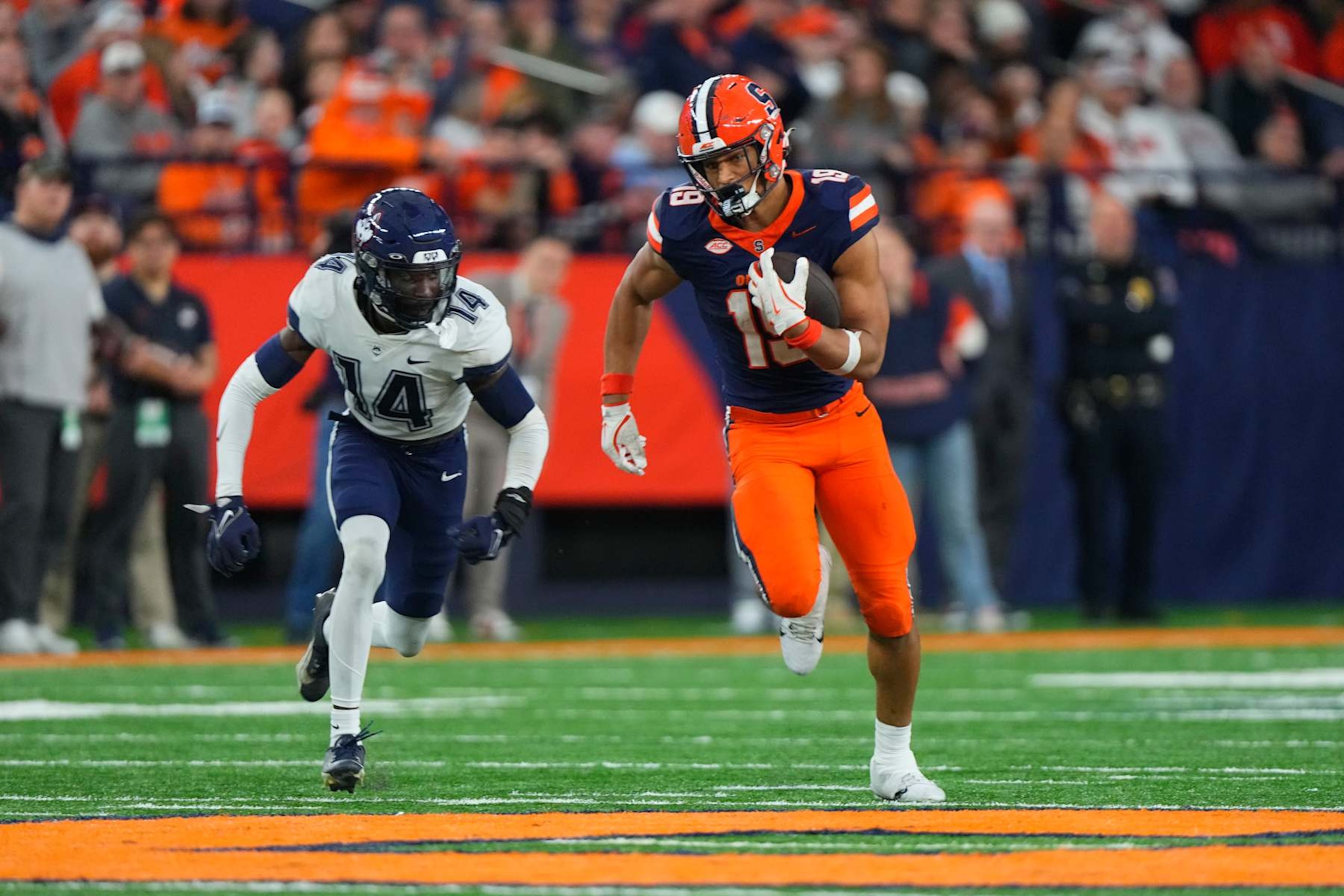 SYRACUSE, NY - NOVEMBER 23: Syracuse Orange Tight End Oronde Gadsden II (19) runs with the ball against Connecticut Huskies Defensive Back Malcolm Bell (14) during the second half of the College Football game between the UConn Huskies and the Syracuse Orange on November 23, 2024, at the JMA Wireless Dome in Syracuse, NY. (Photo by Gregory Fisher/Icon Sportswire via Getty Images)