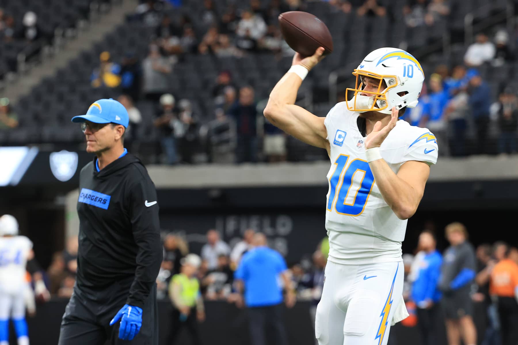 LAS VEGAS, NEVADA - JANUARY 05: Justin Herbert #10 of the Los Angeles Chargers warms up as head coach Jim Harbaugh looks on prior to the game against the Las Vegas Raiders at Allegiant Stadium on January 05, 2025 in Las Vegas, Nevada. (Photo by Ian Maule/Getty Images)