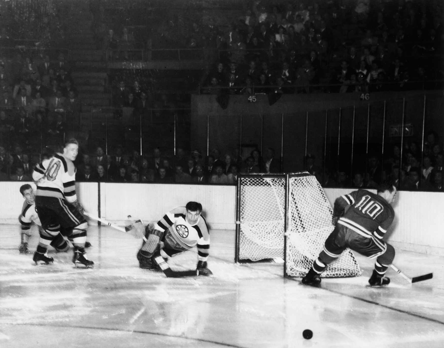 American hockey player Frank Brimsek, goalkeeper for the Boston Bruins, lunges as he makes a save from a shot by the New York Rangers' Edgar Laprade (right) while fellow Bruin Fern Flaman (left) looks back over his shoulder, October 31, 1948. (Photo by Bruce Bennett Studios via Getty Images Studios/Getty Images)