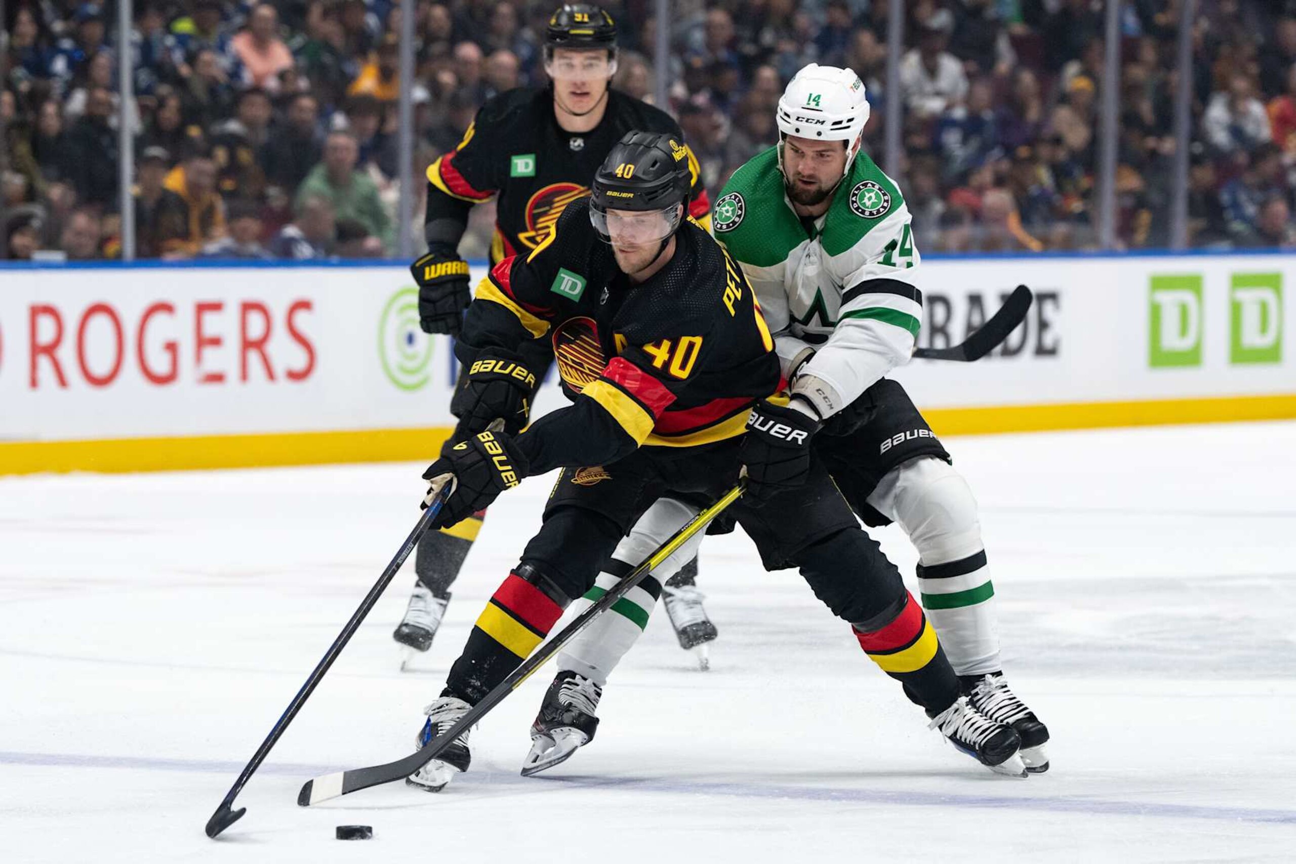 VANCOUVER, CANADA - MARCH 28: Elias Pettersson #40 of the Vancouver Canucks and Jamie Benn #14 of the Dallas Stars fight for the puck during the first period of their NHL Game at Rogers Arena on March 28, 2024 in Vancouver, British Columbia, Canada. (Photo by Ethan Cairns/Getty Images) VANCOUVER, CANADA - MARCH 28: Elias Pettersson #40 of the Vancouver Canucks and Jamie Benn #14 of the Dallas Stars fight for the puck during the first period of their NHL Game at Rogers Arena on March 28, 2024 in Vancouver, British Columbia, Canada. (Photo by Ethan Cairns/Getty Images)