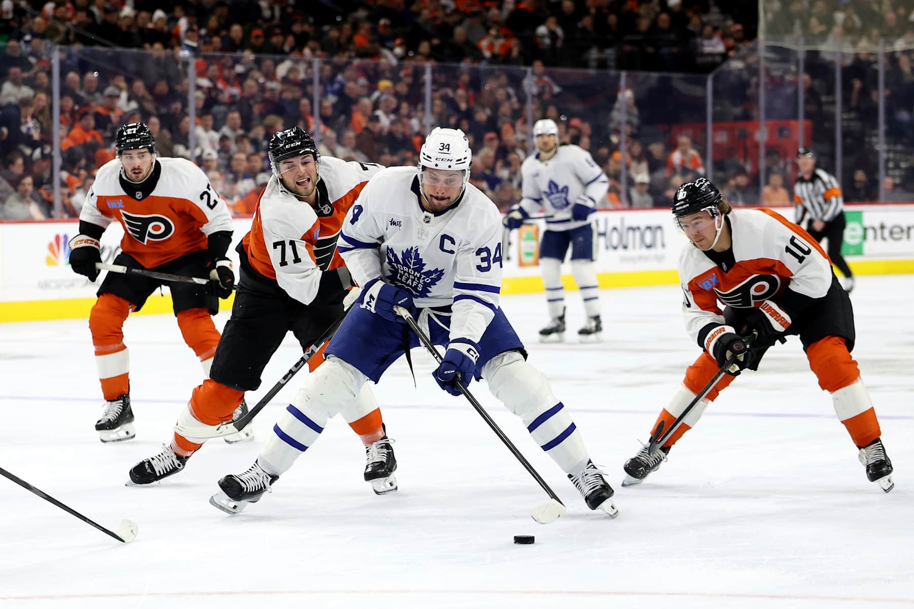 PHILADELPHIA, PENNSYLVANIA - JANUARY 07: Auston Matthews #34 of the Toronto Maple Leafs controls the puck against Tyson Foerster #71 and Bobby Brink #10 of the Philadelphia Flyers during the first period at the Wells Fargo Center on January 07, 2025 in Philadelphia, Pennsylvania. (Photo by Emilee Chinn/Getty Images)
