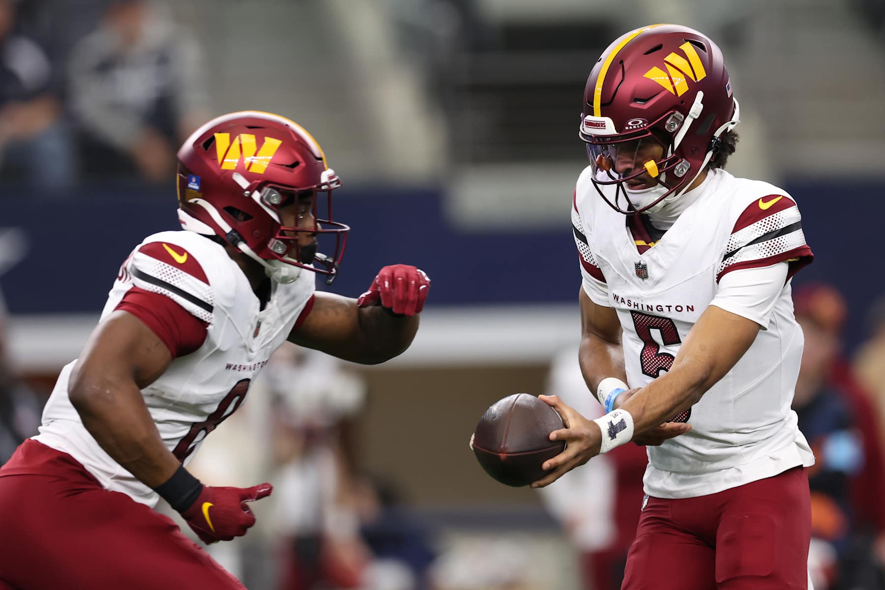 ARLINGTON, TEXAS - JANUARY 05: Jayden Daniels #5 of the Washington Commanders hands the ball off to teammate Brian Robinson Jr. #8 against the Dallas Cowboys during the first quarter at AT&T Stadium on January 05, 2025 in Arlington, Texas. (Photo by Sam Hodde/Getty Images)
