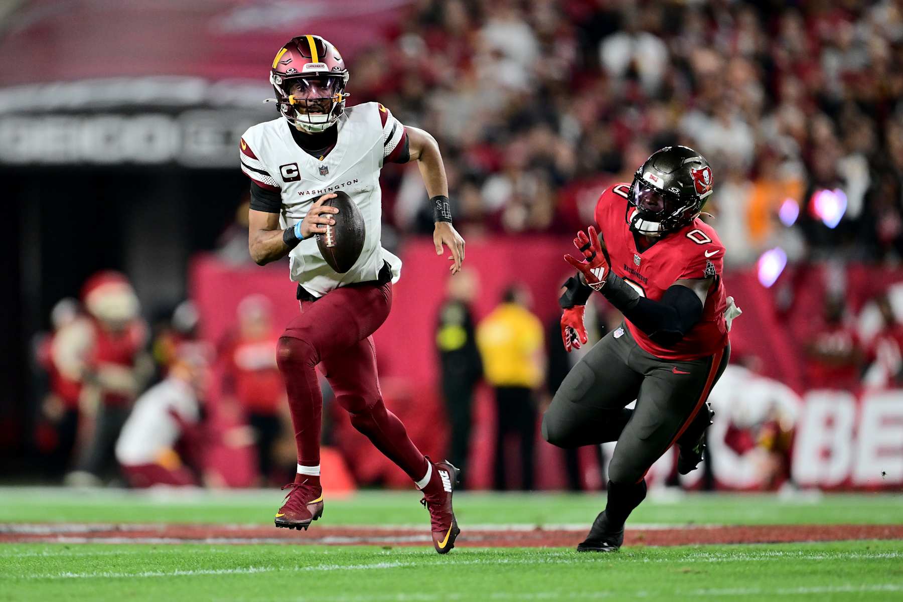TAMPA, FLORIDA - JANUARY 12: Jayden Daniels #5 of the Washington Commanders scrambles against Yaya Diaby #0 of the Tampa Bay Buccaneers during the first quarter in the NFC Wild Card Playoff at Raymond James Stadium on January 12, 2025 in Tampa, Florida. (Photo by Julio Aguilar/Getty Images)