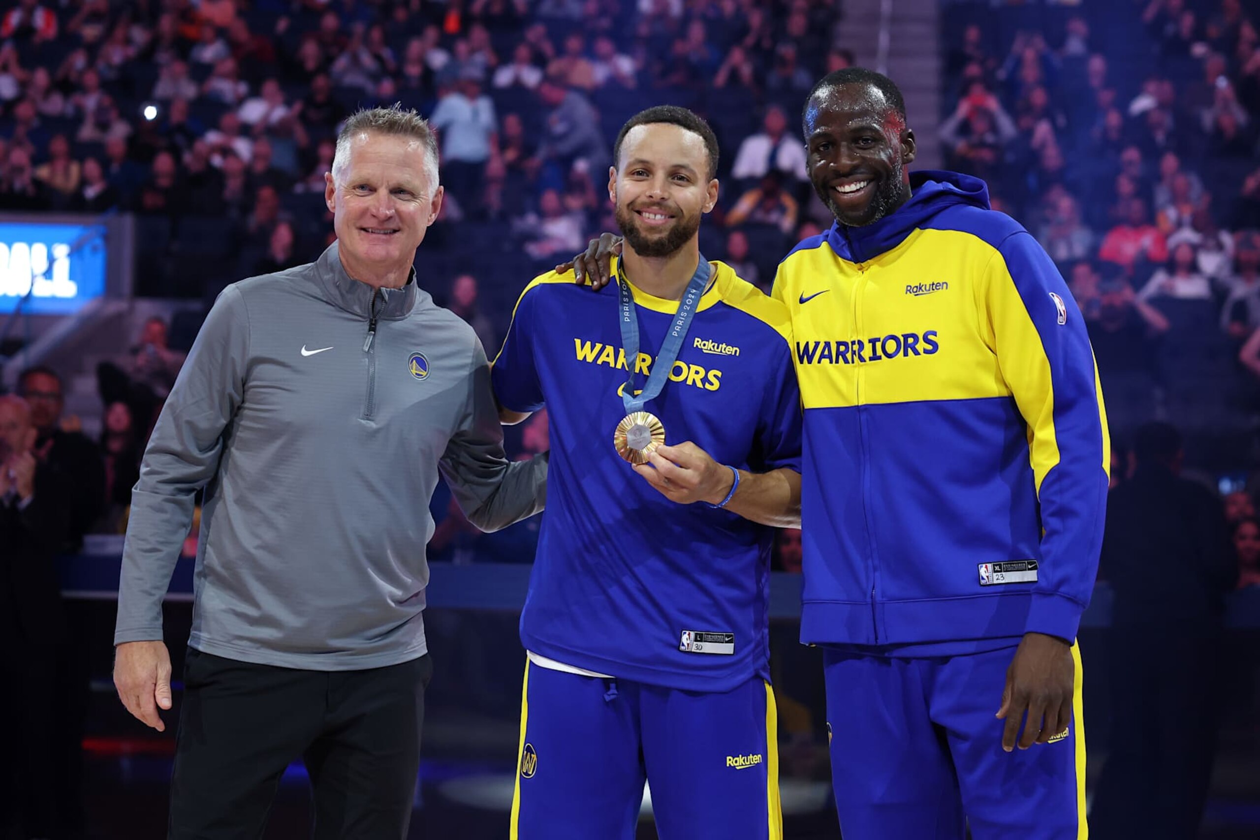 SAN FRANCISCO, CALIFORNIA - OCTOBER 11:  Golden State Warriors head coach Steve Kerr, from left, Stephen Curry #30 and Draymond Green #23 pose for photos during an Olympic Gold Medal recognition ceremony before their preseason game against the Sacramento Kings at Chase Center on October 11, 2024 in San Francisco, California.  NOTE TO USER: User expressly acknowledges and agrees that, by downloading and/or using this photograph, user is consenting to the terms and conditions of the Getty Images License Agreement.  (Photo by Ezra Shaw/Getty Images)
