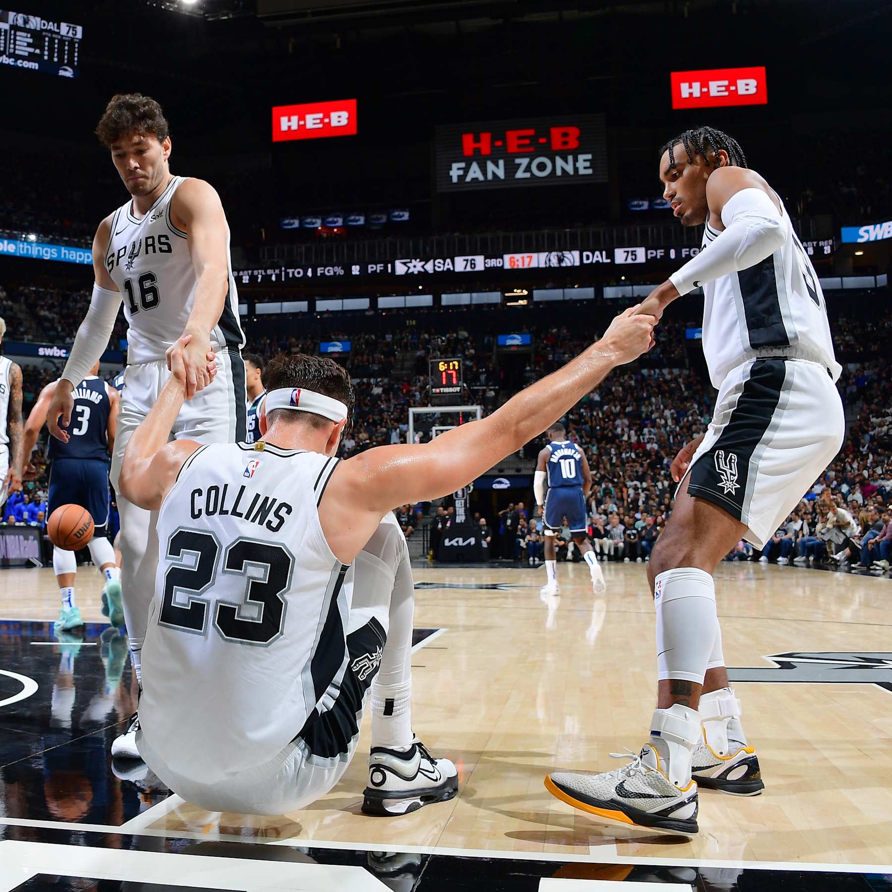 SAN ANTONIO, TX - OCTOBER 25: Zach Collins #23 is helped up by Cedi Osman #16 and Tre Jones #33 of the San Antonio Spurs during the game against the Dallas Mavericks on October 25, 2023 at the Frost Bank Center in San Antonio, Texas. NOTE TO USER: User expressly acknowledges and agrees that, by downloading and or using this photograph, user is consenting to the terms and conditions of the Getty Images License Agreement. Mandatory Copyright Notice: Copyright 2023 NBAE (Photos by Michael Gonzales/NBAE via Getty Images)