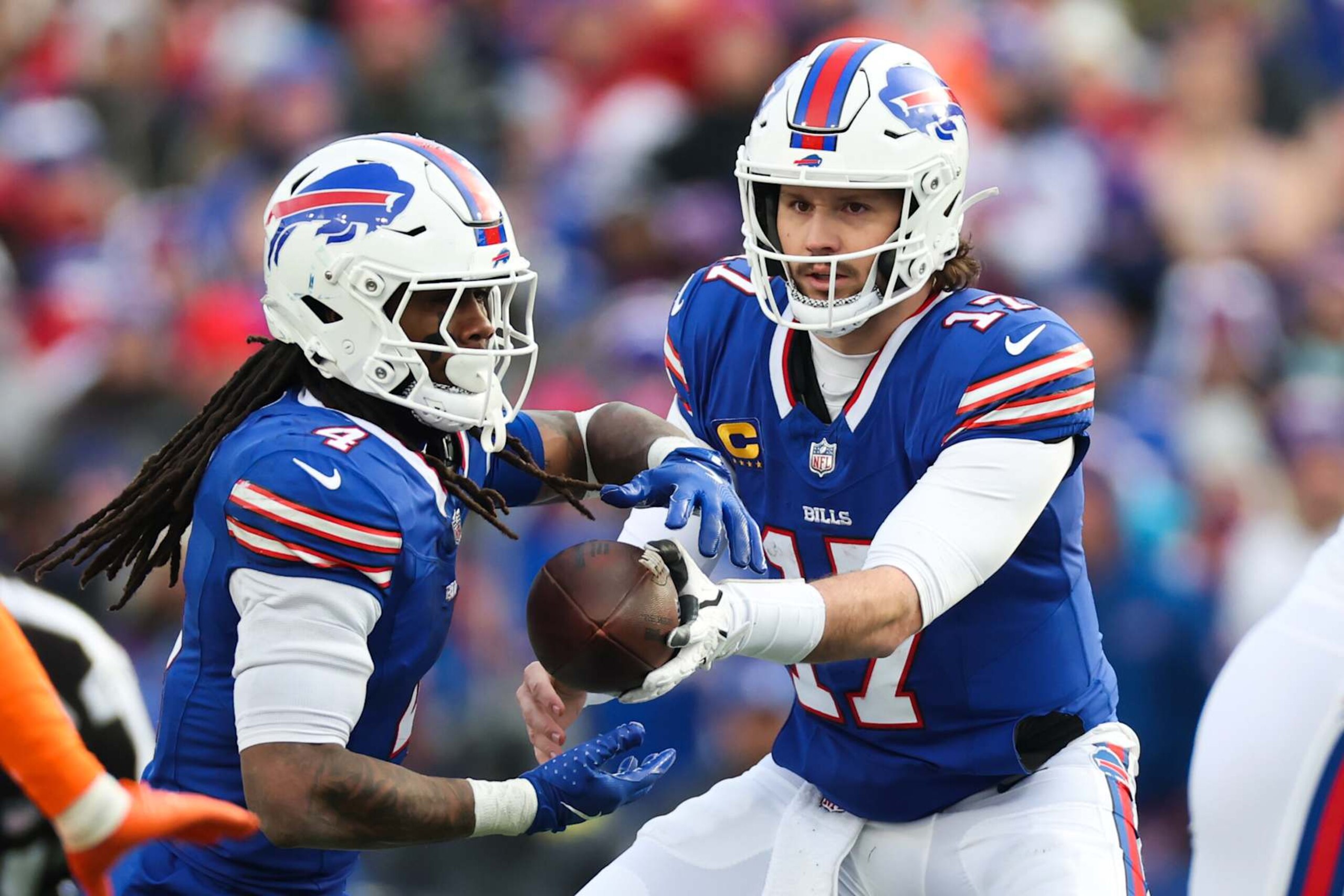 ORCHARD PARK, NEW YORK - JANUARY 12: Josh Allen #17 of the Buffalo Bills hands off the ball to teammate James Cook #4 in the third quarter against the Denver Broncos during the AFC Wild Card Playoffs at Highmark Stadium on January 12, 2025 in Orchard Park, New York. (Photo by Elsa/Getty Images) ORCHARD PARK, NEW YORK - JANUARY 12: Josh Allen #17 of the Buffalo Bills hands off the ball to teammate James Cook #4 in the third quarter against the Denver Broncos during the AFC Wild Card Playoffs at Highmark Stadium on January 12, 2025 in Orchard Park, New York. (Photo by Elsa/Getty Images)