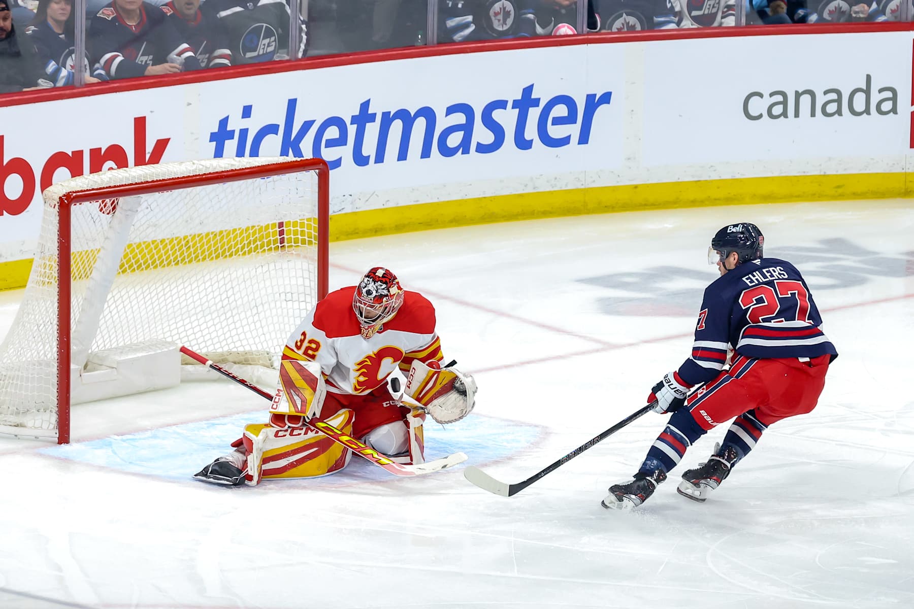 WINNIPEG, CANADA - JANUARY 18:  Goaltender Dustin Wolf #32 of the Calgary Flames makes a stop on Nikolaj Ehlers #27 of the Winnipeg Jets during first period action at the Canada Life Centre on January 18, 2025 in Winnipeg, Manitoba, Canada. (Photo by Jonathan Kozub/NHLI via Getty Images)