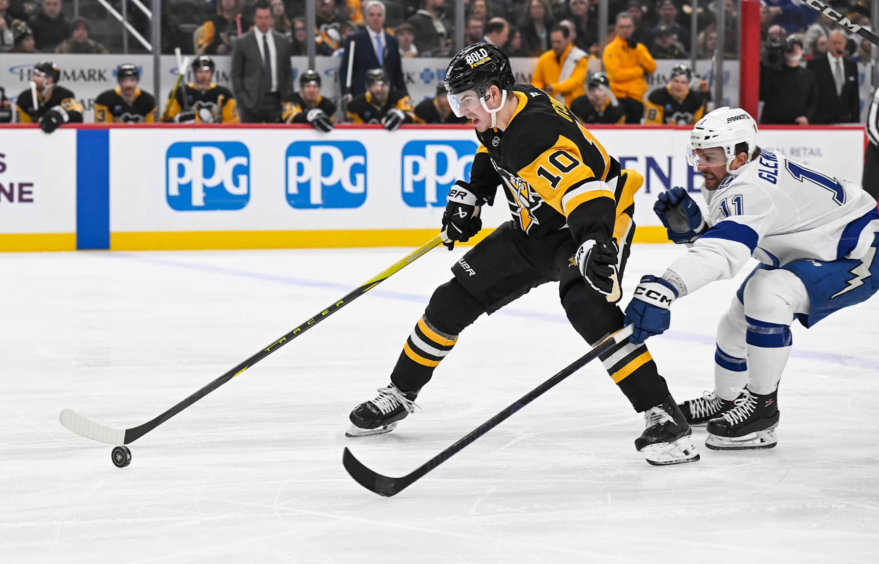 PITTSBURGH, PA - JANUARY 12: Pittsburgh Penguins left wing Drew O'Connor (10) plays the puck against Tampa Bay Lightning center Luke Glendening (11) during the first period in the NHL game between the Pittsburgh Penguins and the Tampa Bay Lightning on January 12, 2025, at PPG Paints Arena in Pittsburgh, PA. (Photo by Jeanine Leech/Icon Sportswire via Getty Images)