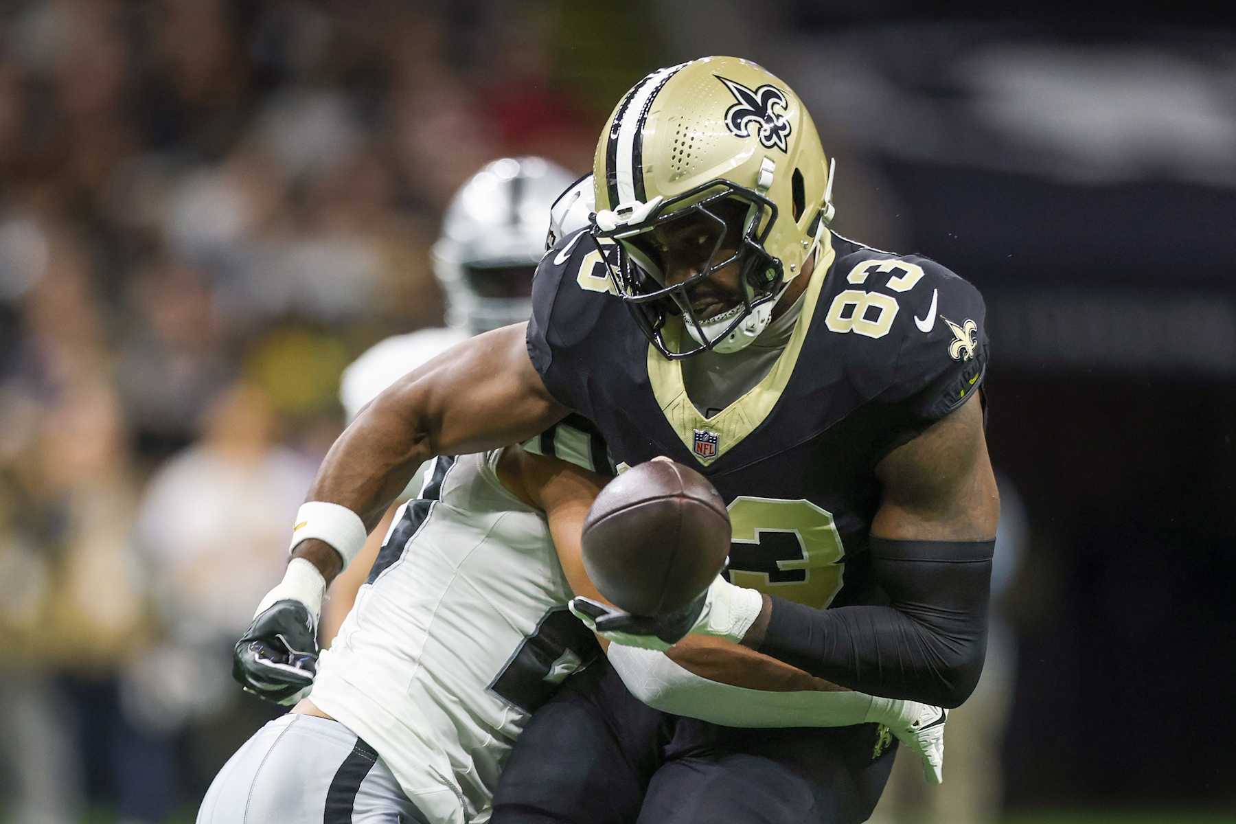 NEW ORLEANS, LOUISIANA - DECEMBER 29: Juwan Johnson #83 of the New Orleans Saints looses control of the ball while being tackled by Isaiah Pola-Mao #20 of the Las Vegas Raiders during the first quarter at Caesars Superdome on December 29, 2024 in New Orleans, Louisiana. (Photo by Chris Graythen/Getty Images)