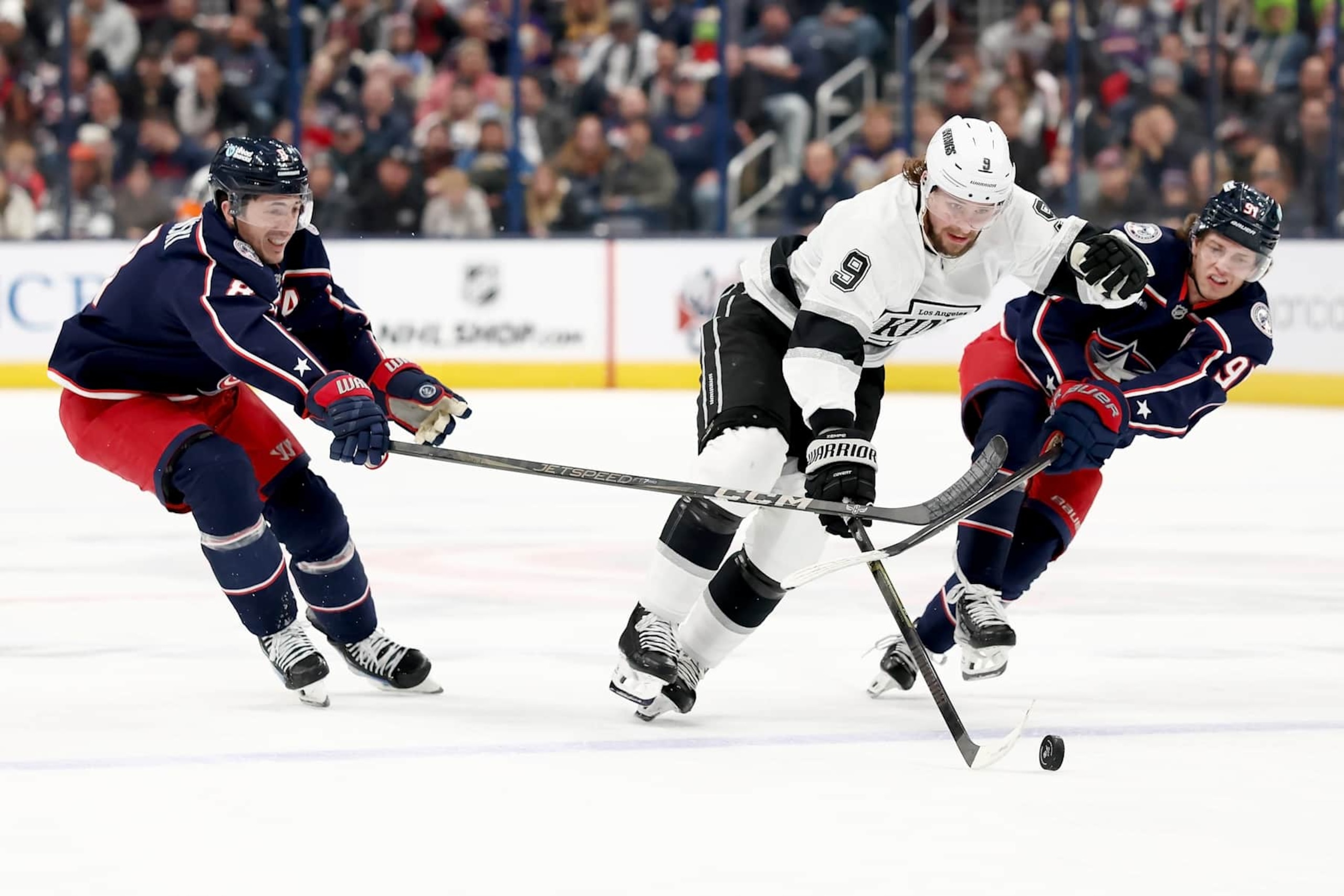 COLUMBUS, OHIO - JANUARY 25:  Zach Werenski #8 of the Columbus Blue Jackets and Kent Johnson #91 attempt to steal the puck from Adrian Kempe #9 of the Los Angeles Kings during the second period of the game at Nationwide Arena on January 25, 2025 in Columbus, Ohio. (Photo by Kirk Irwin/NHLI via Getty Images)