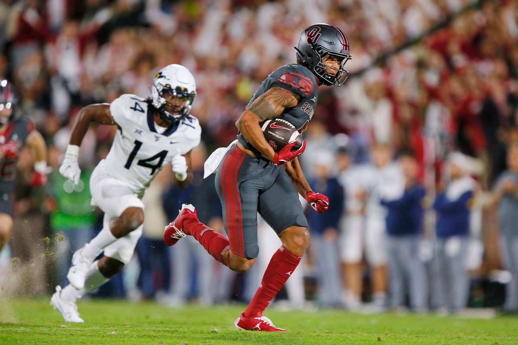 NORMAN, OKLAHOMA - NOVEMBER 11:  Wide receiver Nic Anderson #4 of the Oklahoma Sooners runs with a deep pass for 63 yards against linebacker cornerback Malachi Ruffin #14 of the West Virginia Mountaineers in the second quarter at Gaylord Family Oklahoma Memorial Stadium on November 11, 2023 in Norman, Oklahoma. Oklahoma won 59-20. (Photo by Brian Bahr/Getty Images)