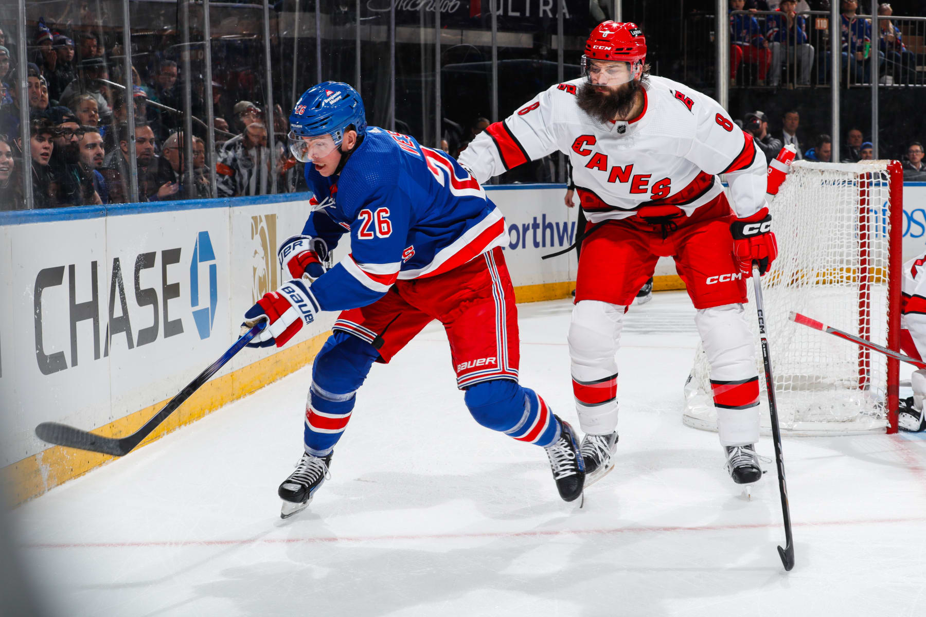 NEW YORK, NEW YORK - JANUARY 02:  Jimmy Vesey #26 of the New York Rangers skates with the puck against Brent Burns #8 of the Carolina Hurricanes at Madison Square Garden on January 2, 2024 in New York City. (Photo by Jared Silber/NHLI via Getty Images)
