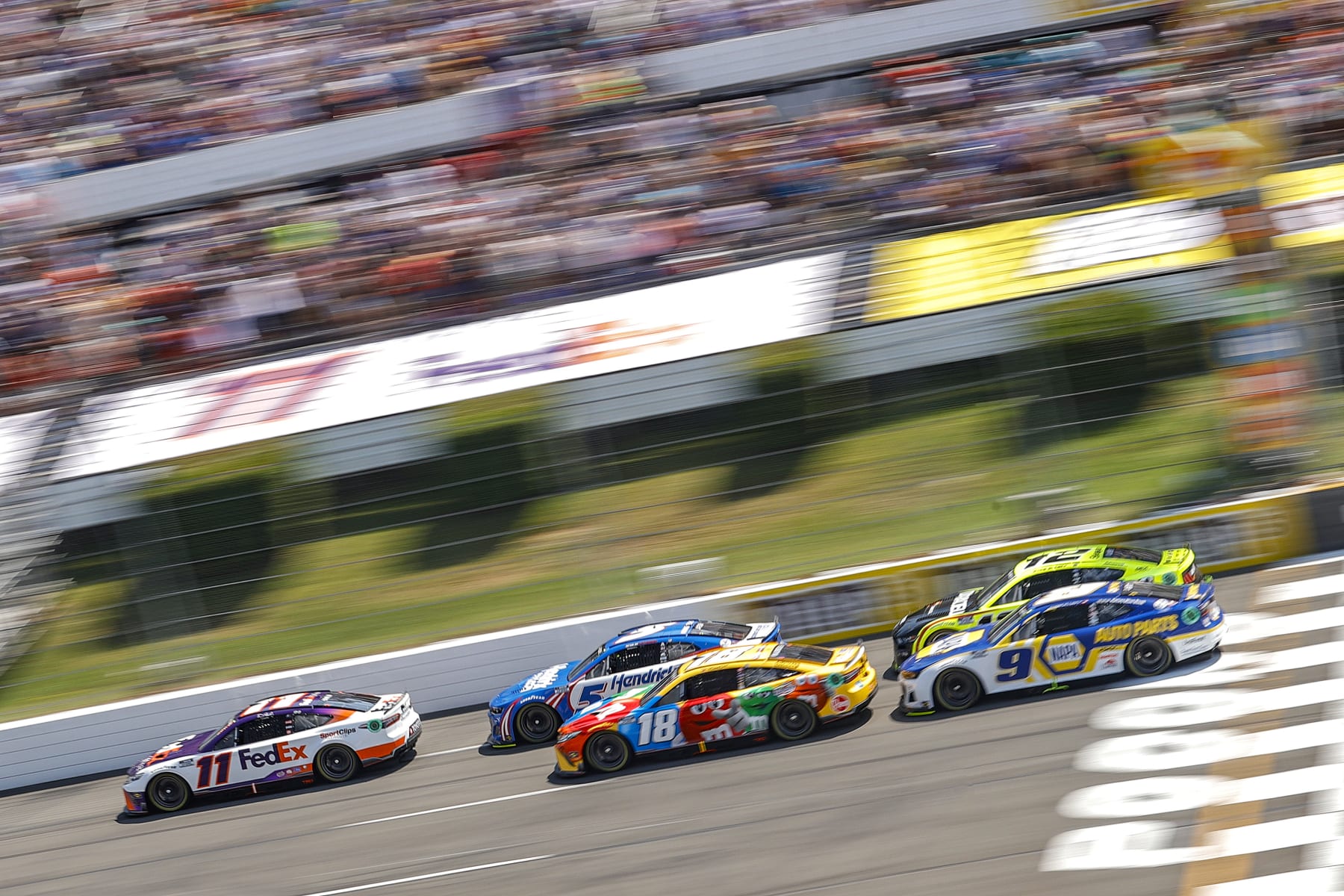 LONG POND, PENNSYLVANIA - JULY 24: Denny Hamlin, driver of the #11 FedEx Office Toyota, Kyle Busch, driver of the #18 M&Ms Toyota, Kyle Larson, driver of the #5 HendrickCars.com Chevrolet, Chase Elliott, driver of the #9 NAPA Auto Parts Chevrolet, and Ryan Blaney, driver of the #12 Menards/Duracell Ford, lead the field to start the NASCAR Cup Series M&M's Fan Appreciation 400 at Pocono Raceway on July 24, 2022 in Long Pond, Pennsylvania. (Photo by Tim Nwachukwu/Getty Images)