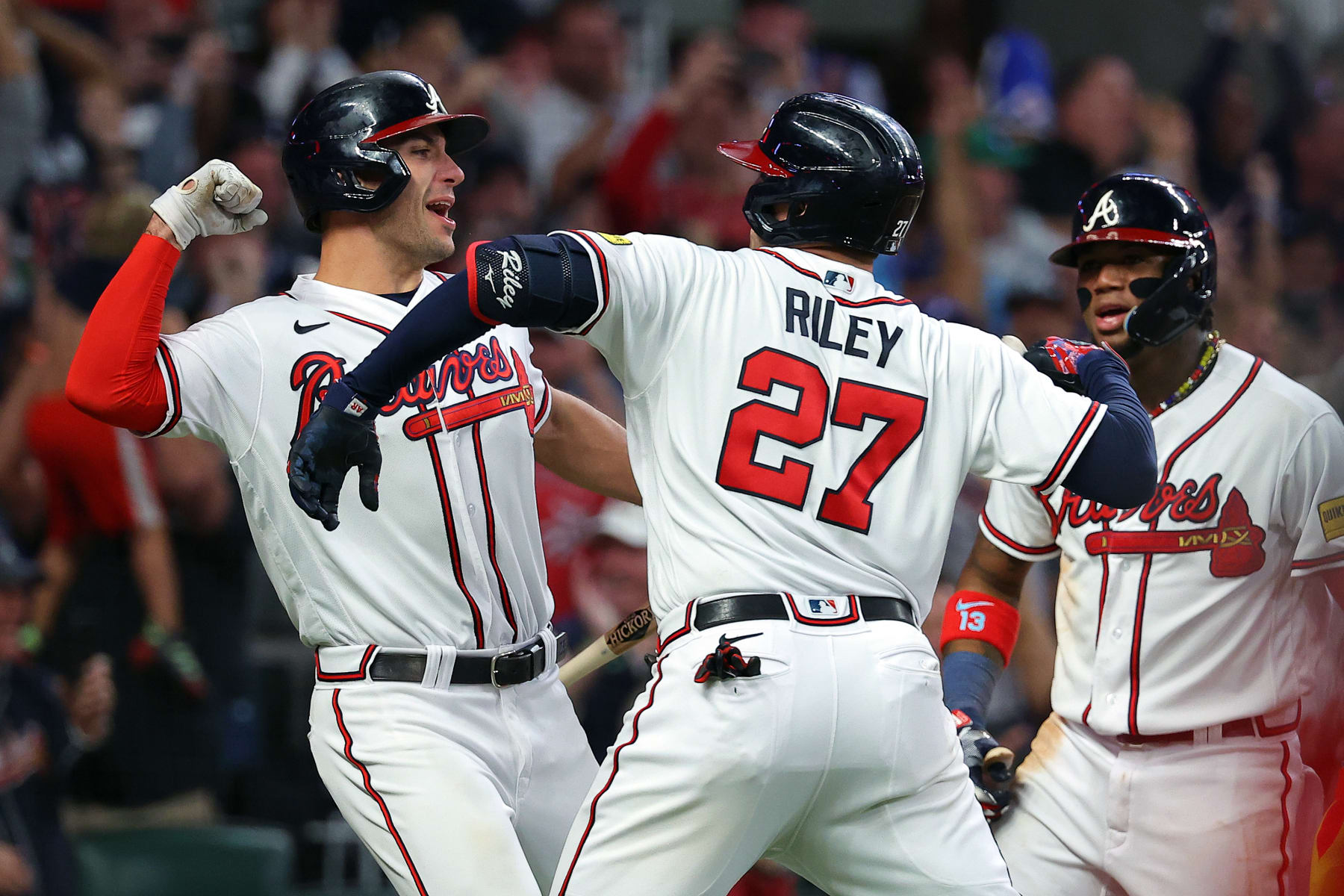 ATLANTA, GEORGIA - OCTOBER 09: Austin Riley #27 celebrates with Matt Olson #28 and Ronald Acuna Jr. #13 of the Atlanta Braves after hitting a two-run home run in the eighth inning against the Philadelphia Phillies during Game Two of the Division Series at Truist Park on October 09, 2023 in Atlanta, Georgia. (Photo by Kevin C. Cox/Getty Images)