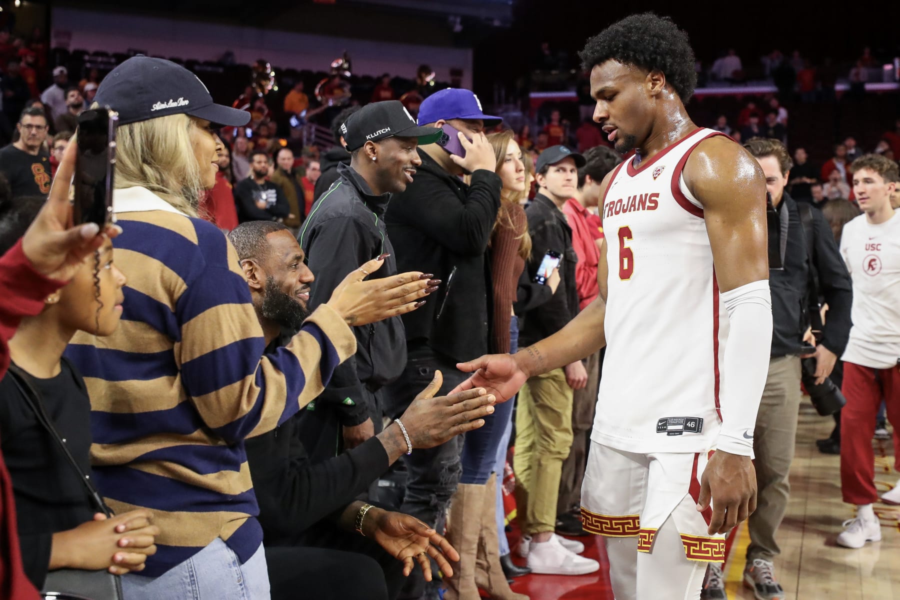 LOS ANGELES, CALIFORNIA - JANUARY 06: Bronny James #6 of the USC Trojans greets parents LeBron James of the Los Angeles Lakers and Savannah James after the game against the Stanford Cardinal at Galen Center on January 06, 2024 in Los Angeles, California. (Photo by Meg Oliphant/Getty Images)