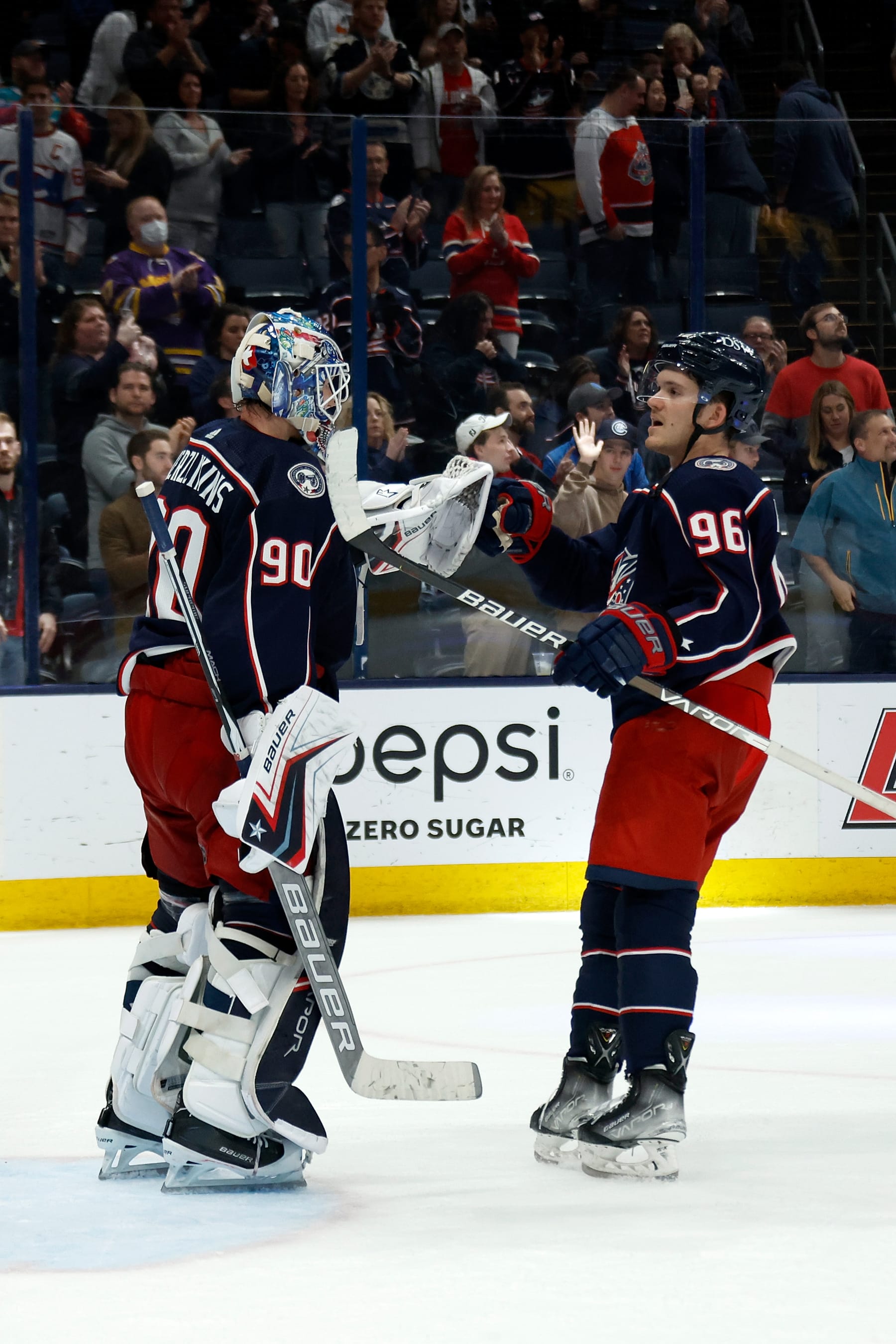 COLUMBUS, OH - APRIL 13:  Elvis Merzlikins #90 of the Columbus Blue Jackets is congratulated by Jack Roslovic #96 after defeating the Montreal Canadiens at Nationwide Arena on April 13, 2022 in Columbus, Ohio. Columbus defeated Montreal 5-1. (Photo by Kirk Irwin/Getty Images)