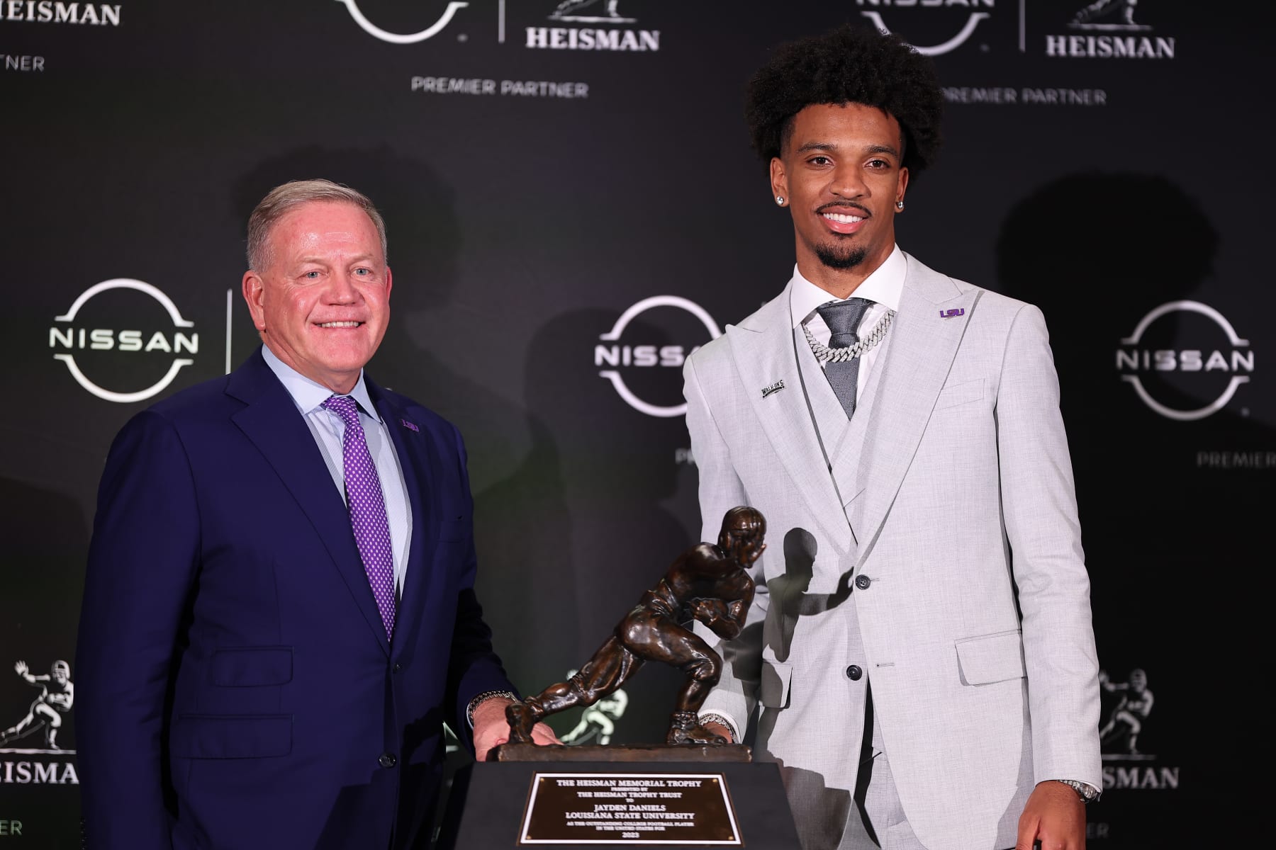 NEW YORK, NY - DECEMBER 09: Jayden Daniels quarterback LSU takes a photo with his head coach Brian Kelly and  the Heisman Trophy after winning it at the press conference at the New York Marriott Marquis on December 9, 2023 in New York City, New York.  (Photo by Rich Graessle/Icon Sportswire via Getty Images)