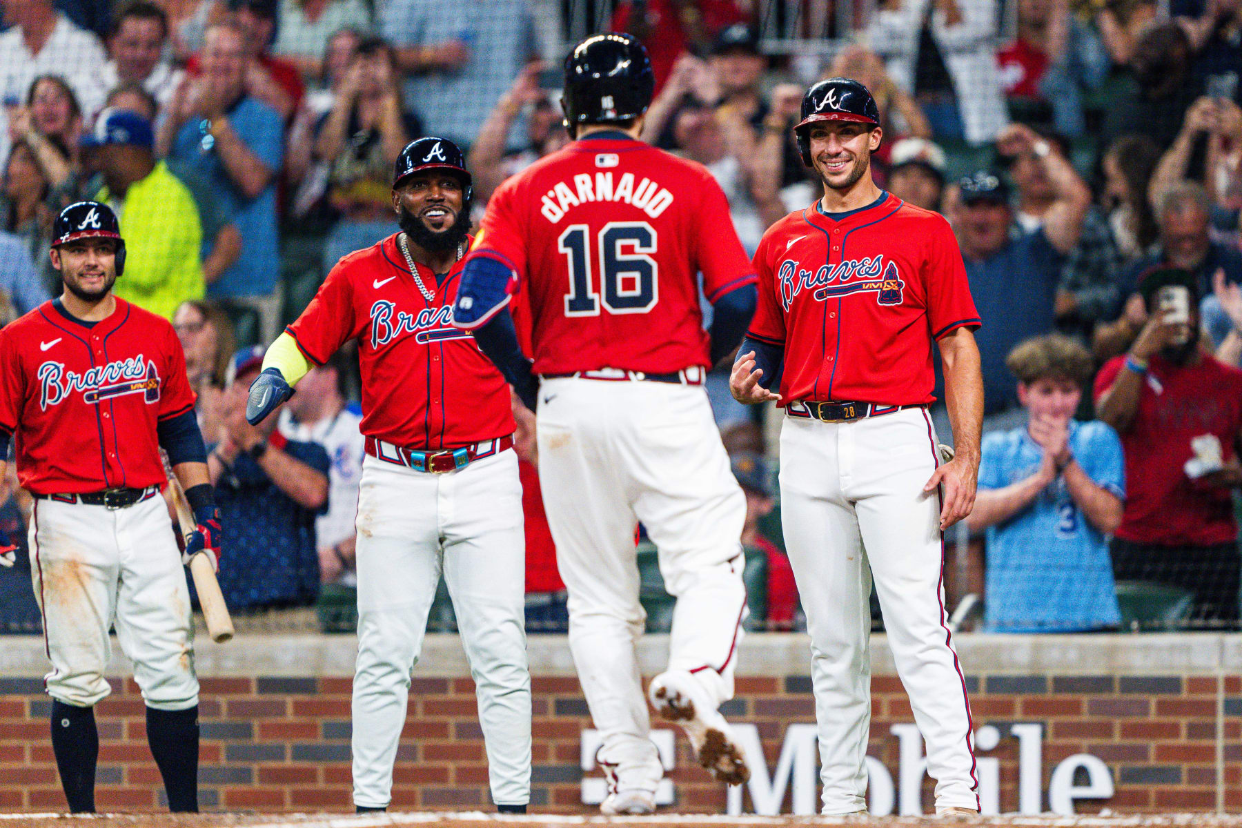 ATLANTA, GA - APRIL 19: David Fletcher #22, Marcell Ozuna #20 and Matt Olson #28 celebrate with Travis d'Arnaud #16 of the Atlanta Braves after d'Arnaud hit a grand slam - his third home run of the game - in the sixth inning against the Texas Rangers at Truist Park on April 19, 2024 in Atlanta, Georgia. (Photo by Matthew Grimes Jr./Atlanta Braves/Getty Images)