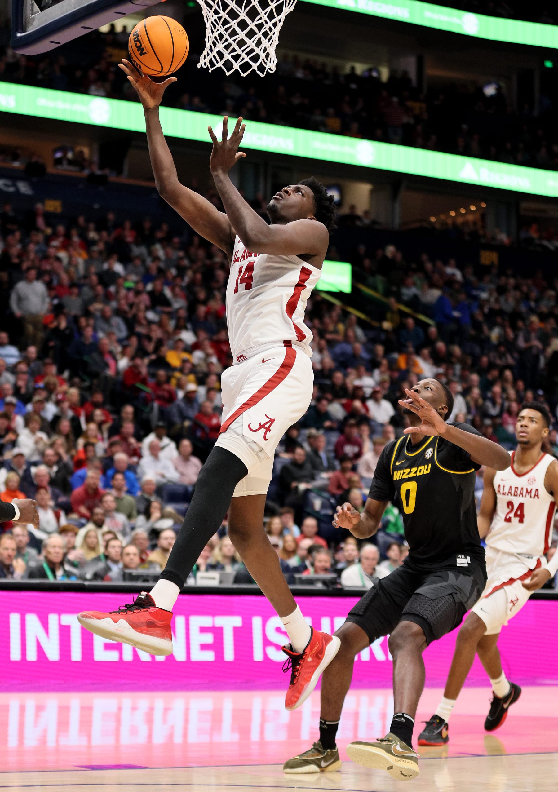 NASHVILLE, TENNESSEE - MARCH 11: Charles Bediako #14 of the Alabama Crimson Tide heads for the net as Mohamed Diarra #0 of the Missouri Tigers defends during the second half of the SEC Basketball Tournament Semifinals at Bridgestone Arena on March 11, 2023 in Nashville, Tennessee. (Photo by Andy Lyons/Getty Images)