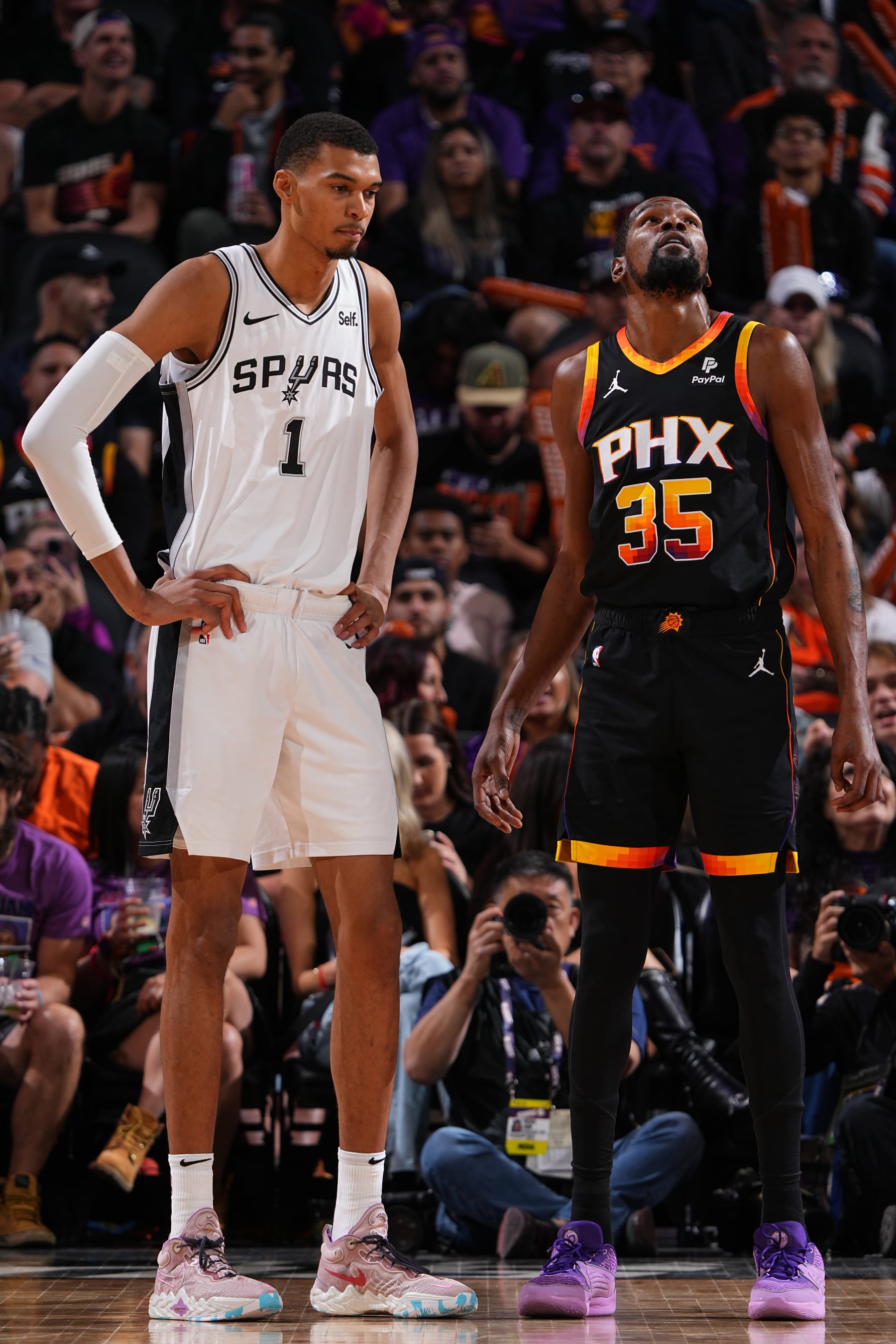 PHOENIX, AZ - OCTOBER 31: Victor Wembanyama #1 of the San Antonio Spurs and Kevin Durant #35 of the Phoenix Suns look on during the game on October 31, 2023 at Footprint Center in Phoenix, Arizona. NOTE TO USER: User expressly acknowledges and agrees that, by downloading and or using this photograph, user is consenting to the terms and conditions of the Getty Images License Agreement. Mandatory Copyright Notice: Copyright 2023 NBAE (Photo by Garrett Ellwood/NBAE via Getty Images)