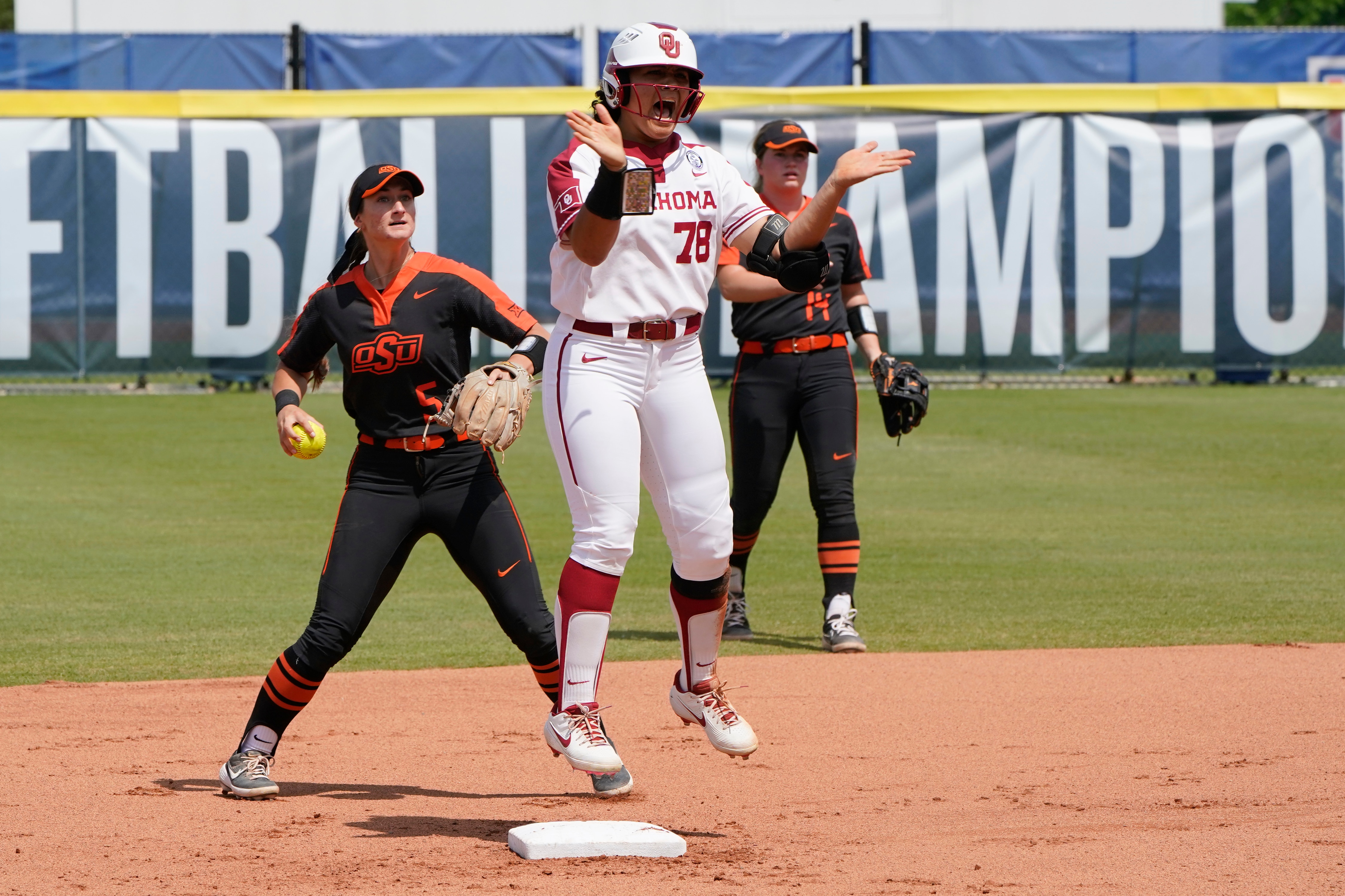 Oklahoma's Jocelyn Alo (78) celebrates a double at second base in front of Oklahoma State's Kiley Naomi (5) in the first inning of the NCAA college Big 12 Championship softball game Saturday, May 15, 2021, in Oklahoma City. (AP Photo/Sue Ogrocki)